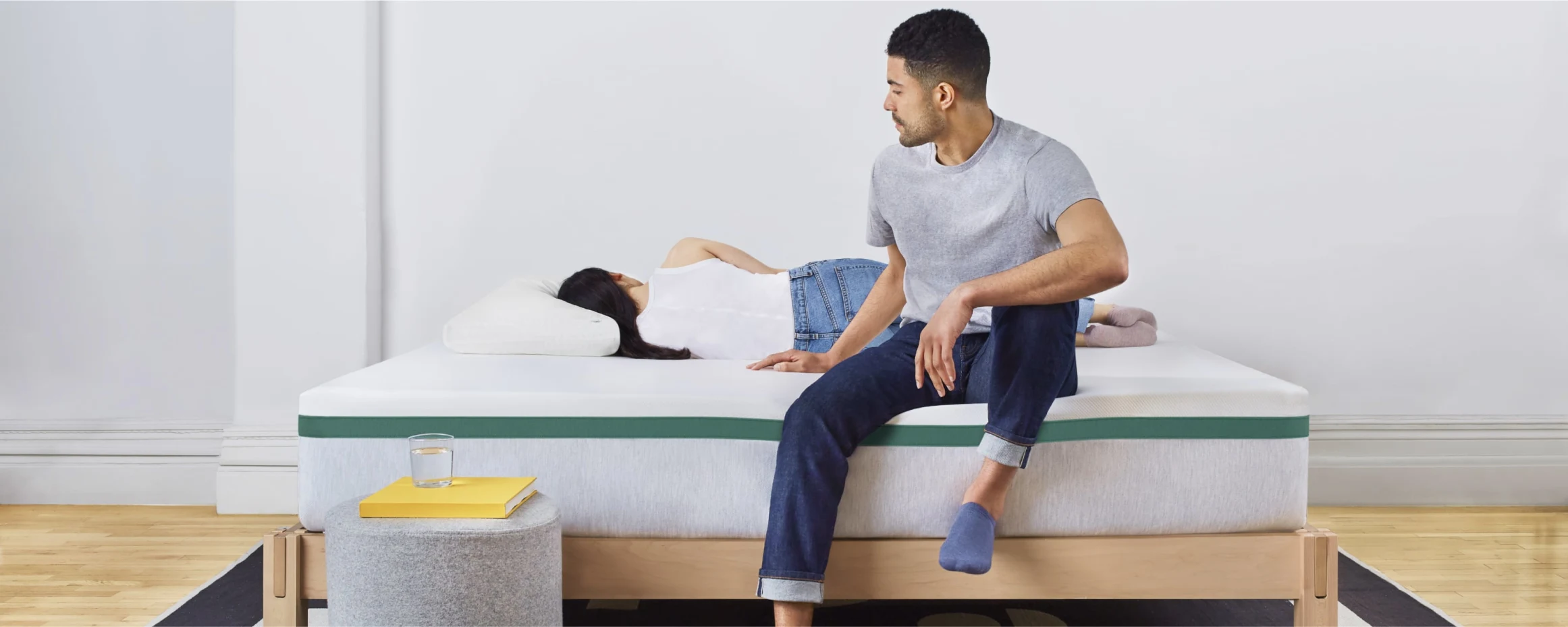 A man sits on a Helix Twilight mattress while a woman lies down.