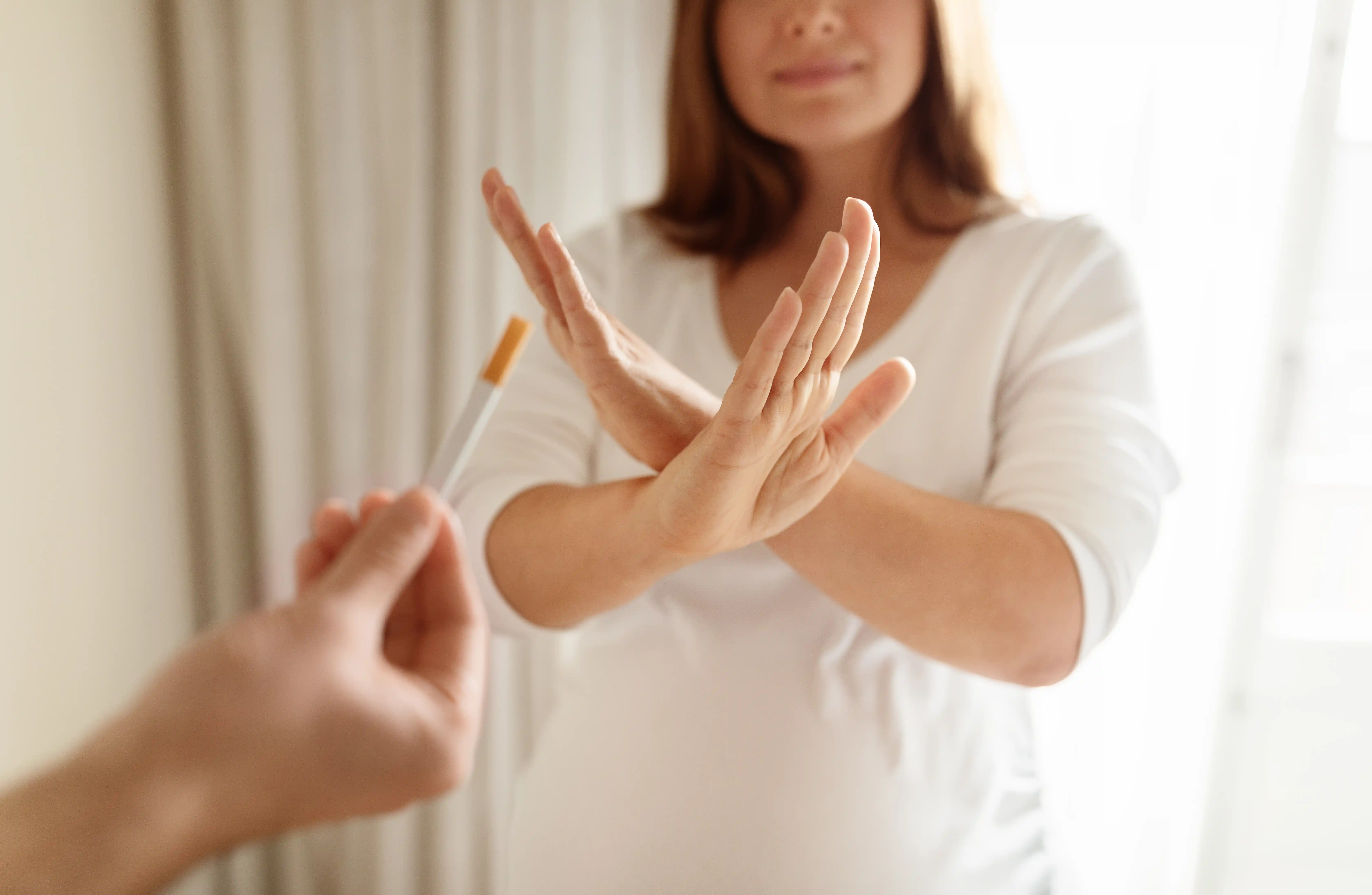 Pregnant woman refusing a cigarette in a well-lit indoor environment