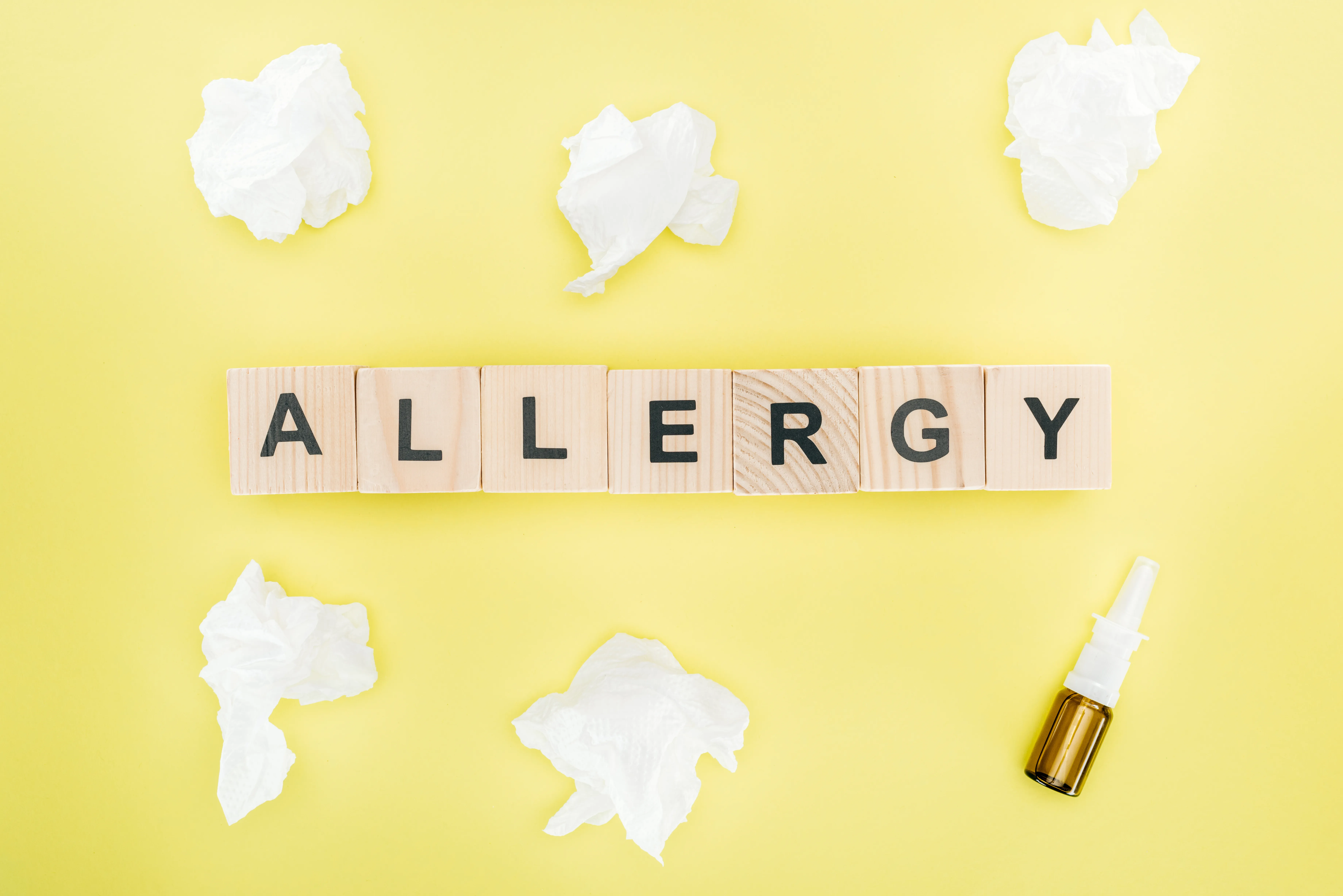 top view of wooden blocks with word allergy near napkins and nasal spray isolated on yellow