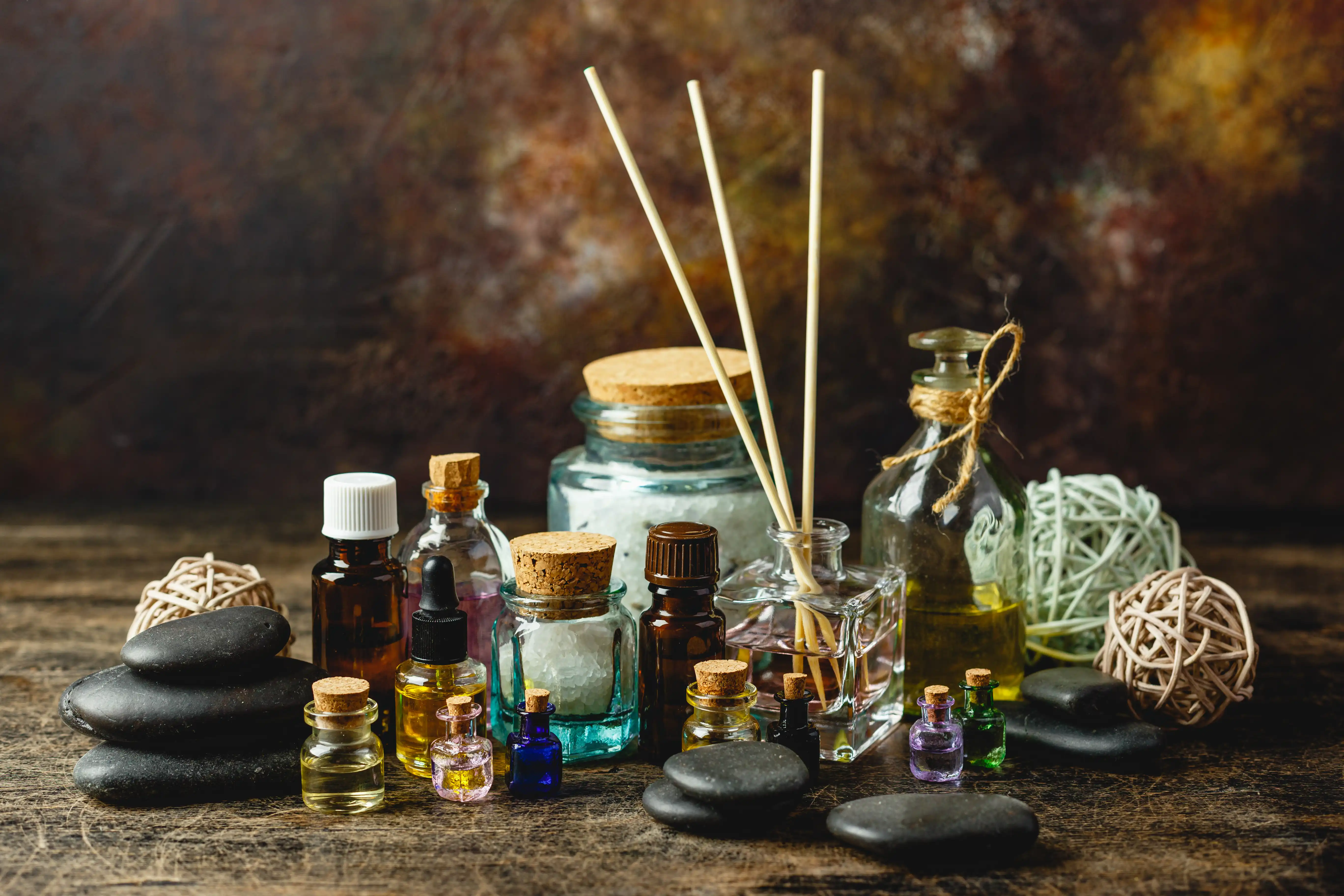 Glass bottles aroma oil and zen stones on wooden table. Spa Treatment