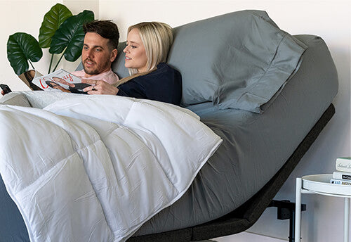 A couple is reading on a raised adjustable bed in a modern bedroom.