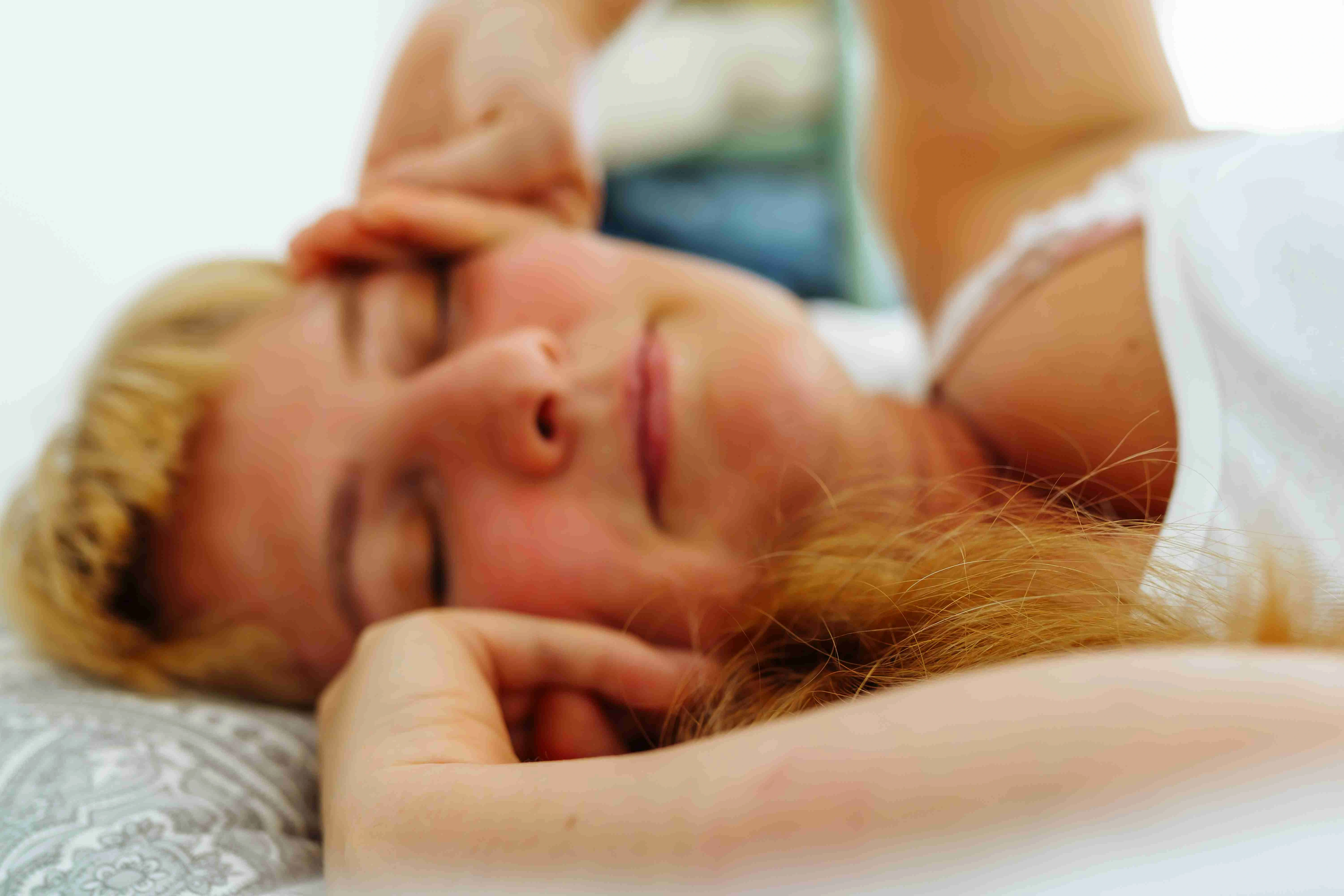 Attractive blonde woman waking up in bed