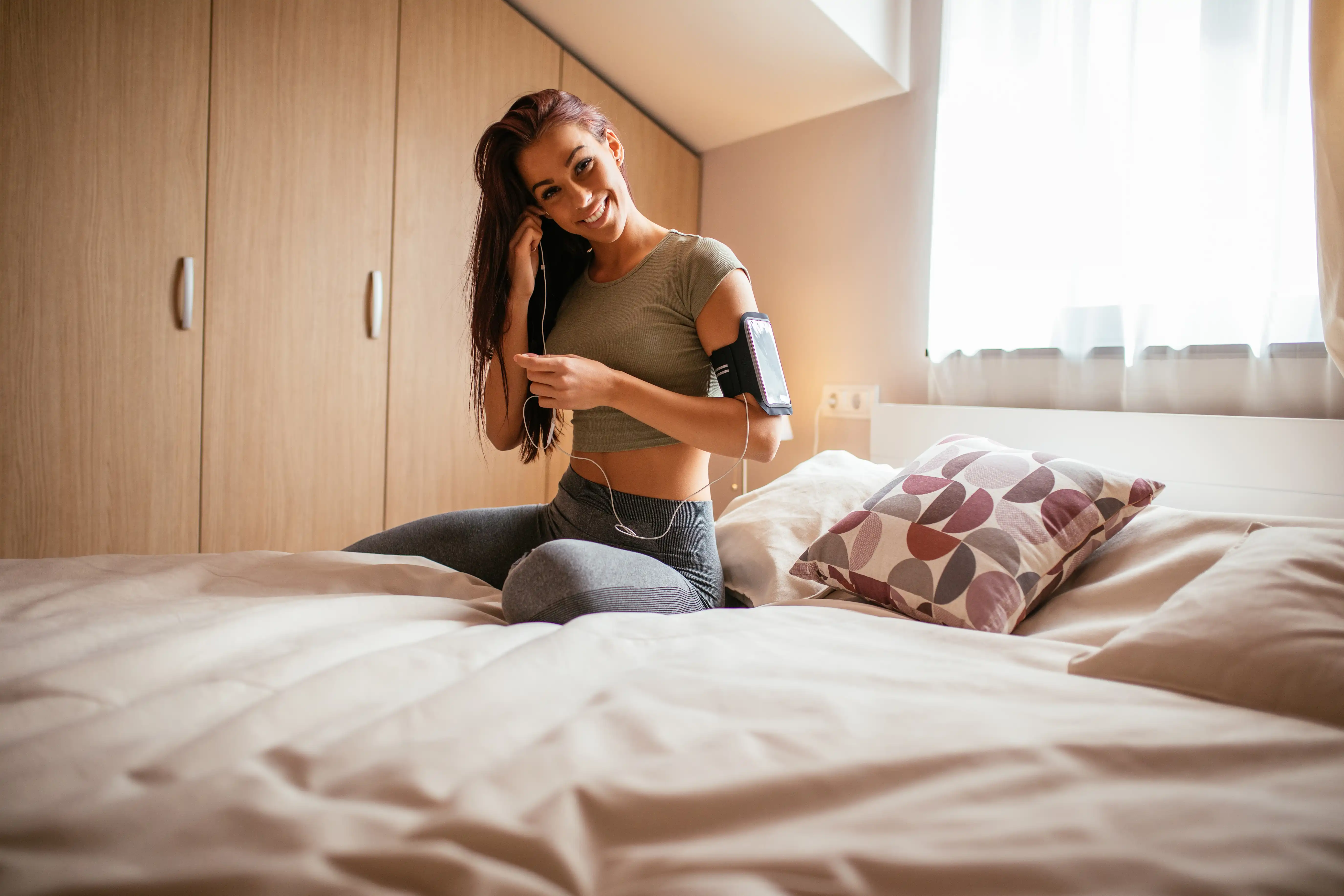 Woman setting her running playlist while sitting in bed.