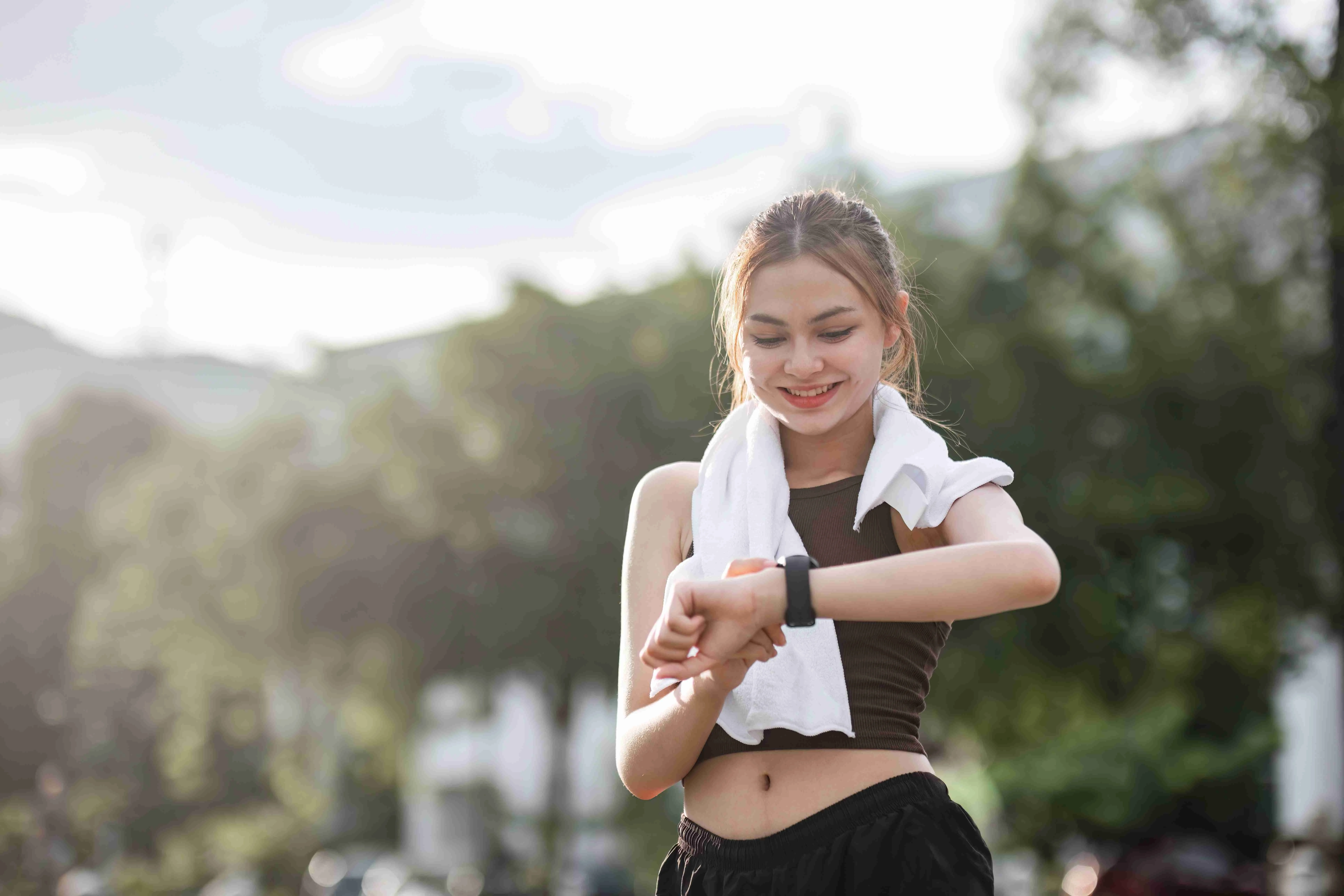 Young woman jogging and looking at his smart watch in the evening at the park.