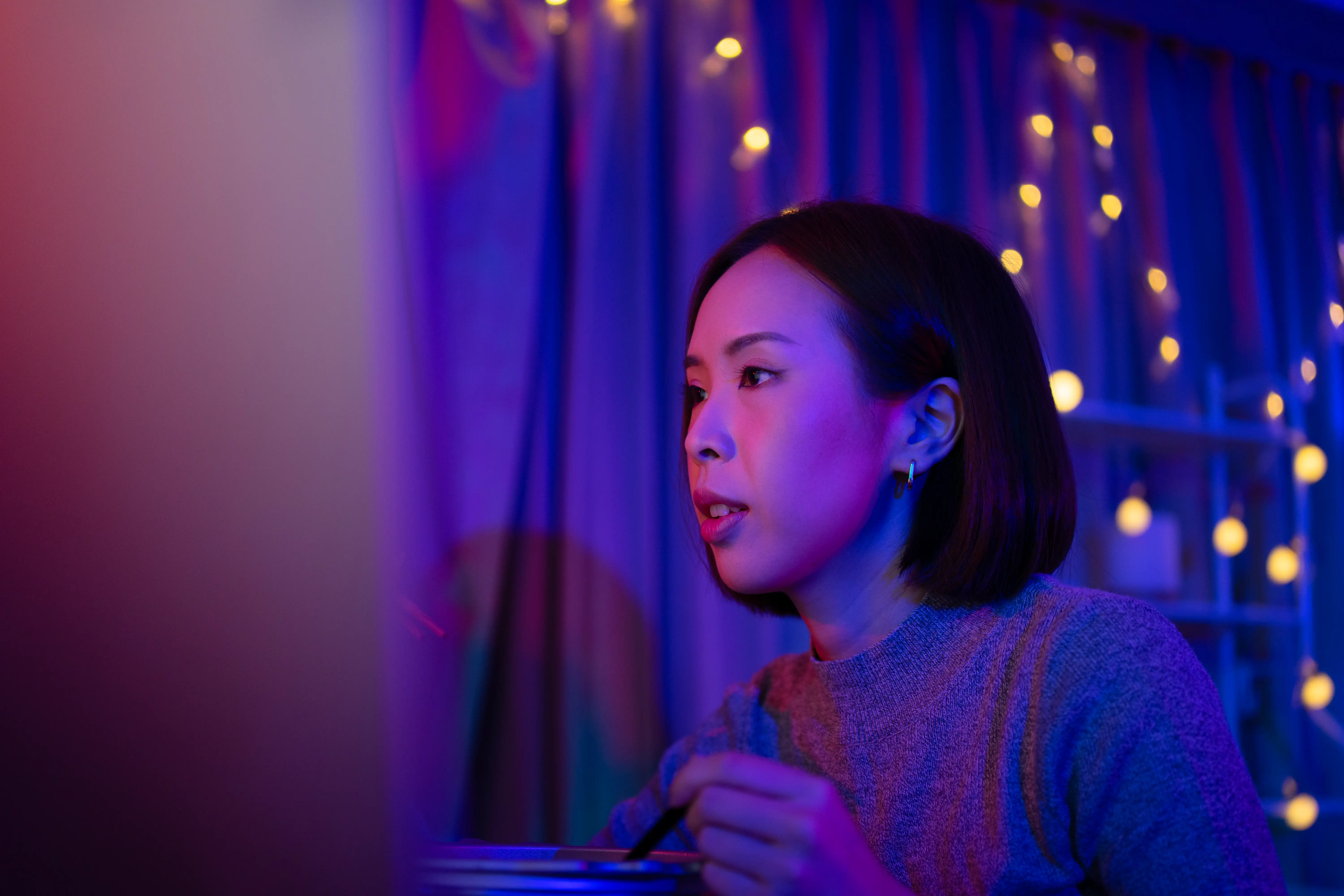Pretty woman is playing game with computer in her room.