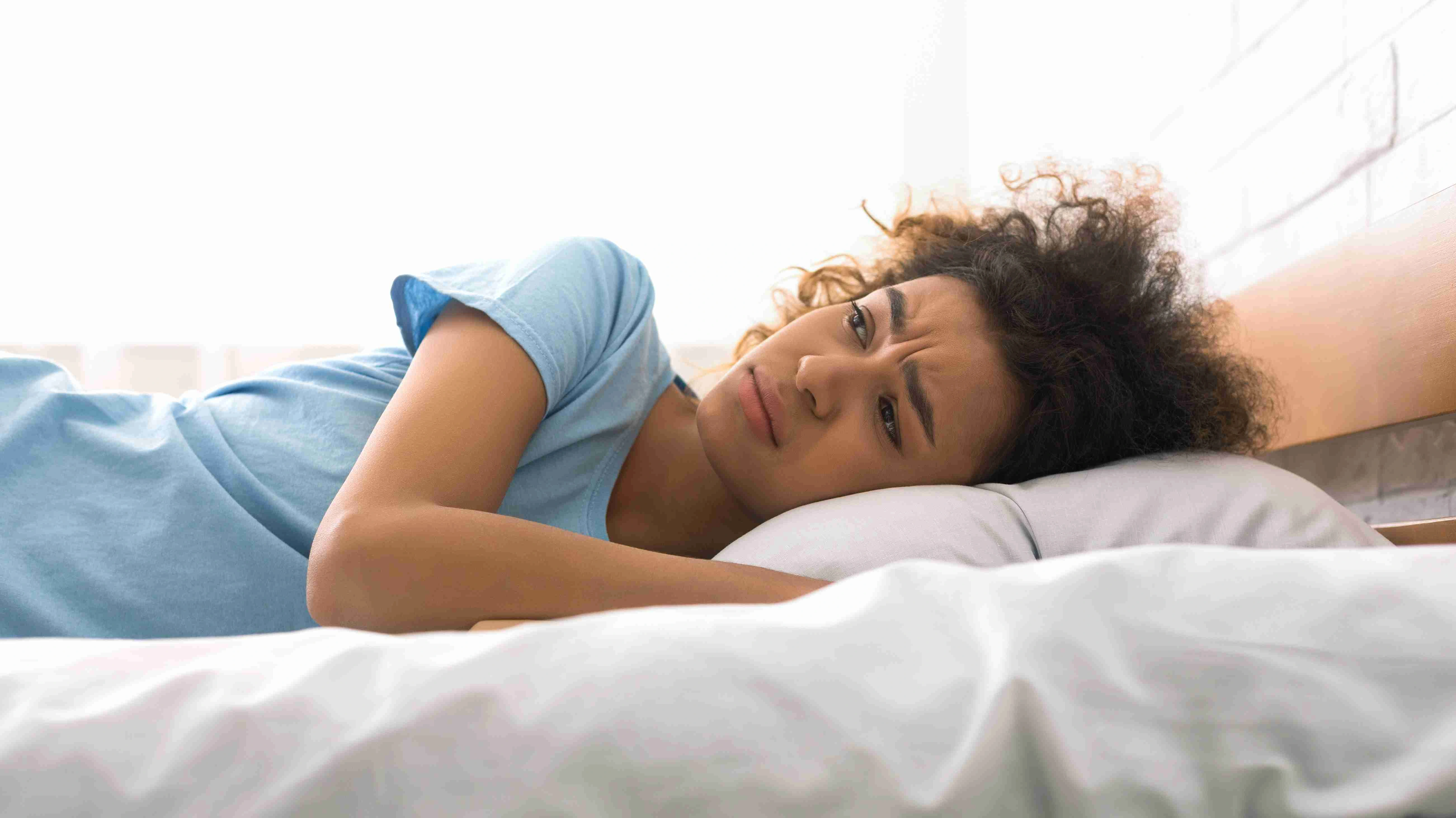 Unhappy woman suffering from insomnia, lying in bed