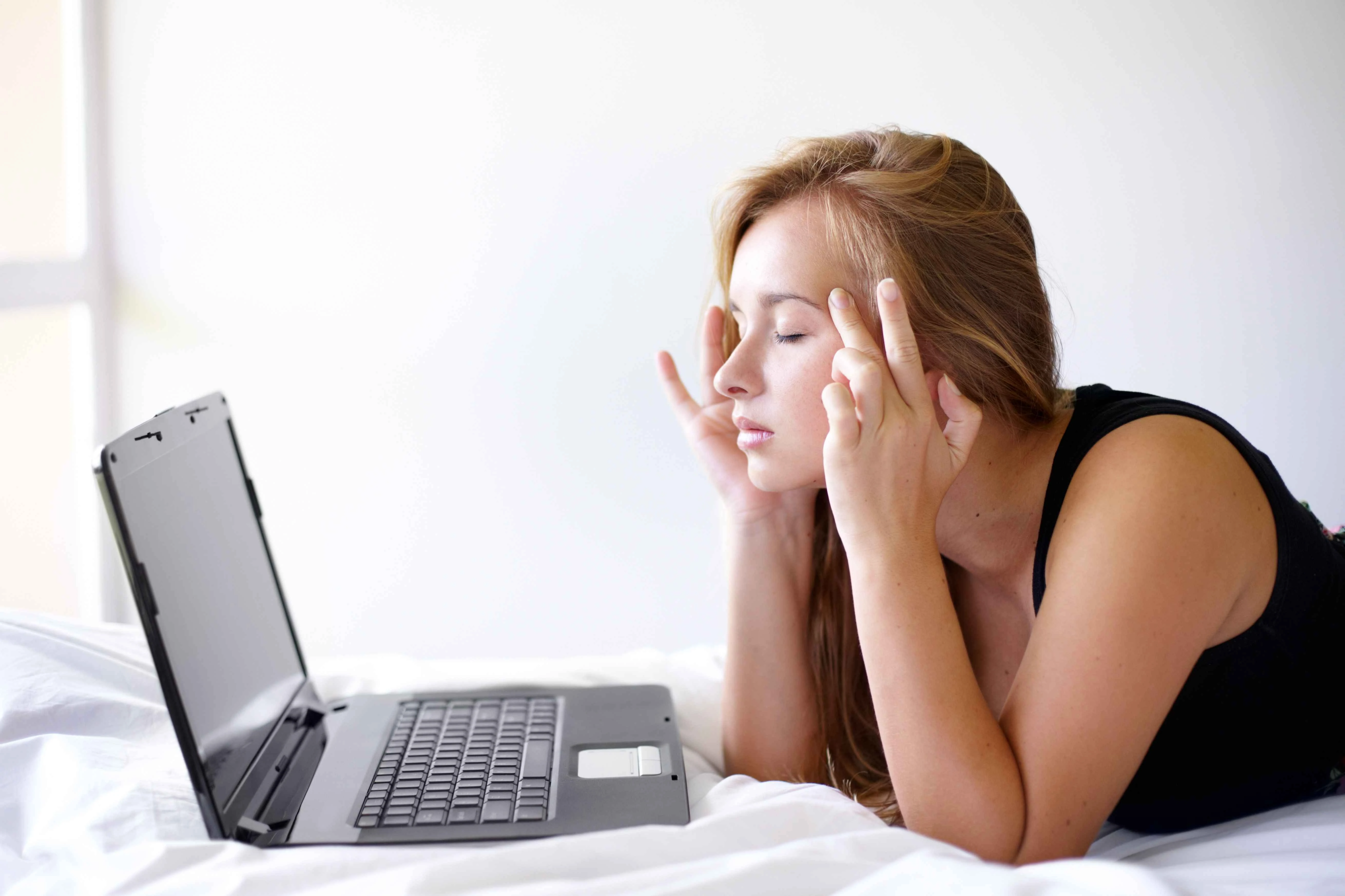 Shot of a beautiful young woman looking frustrated while using a laptop on her bed