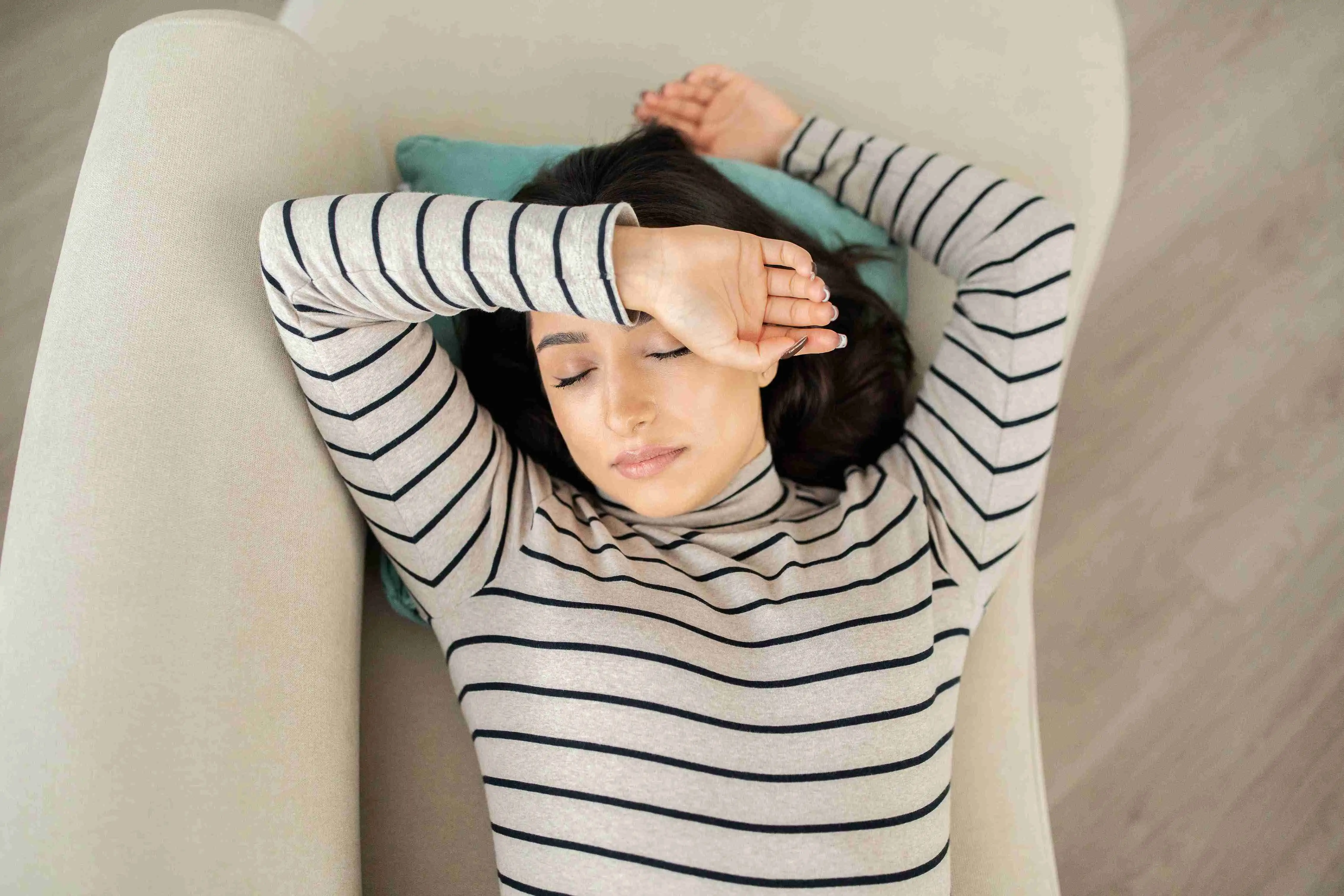 Tired calm millennial Caucasian woman sleep with closed eyes on sofa in living room