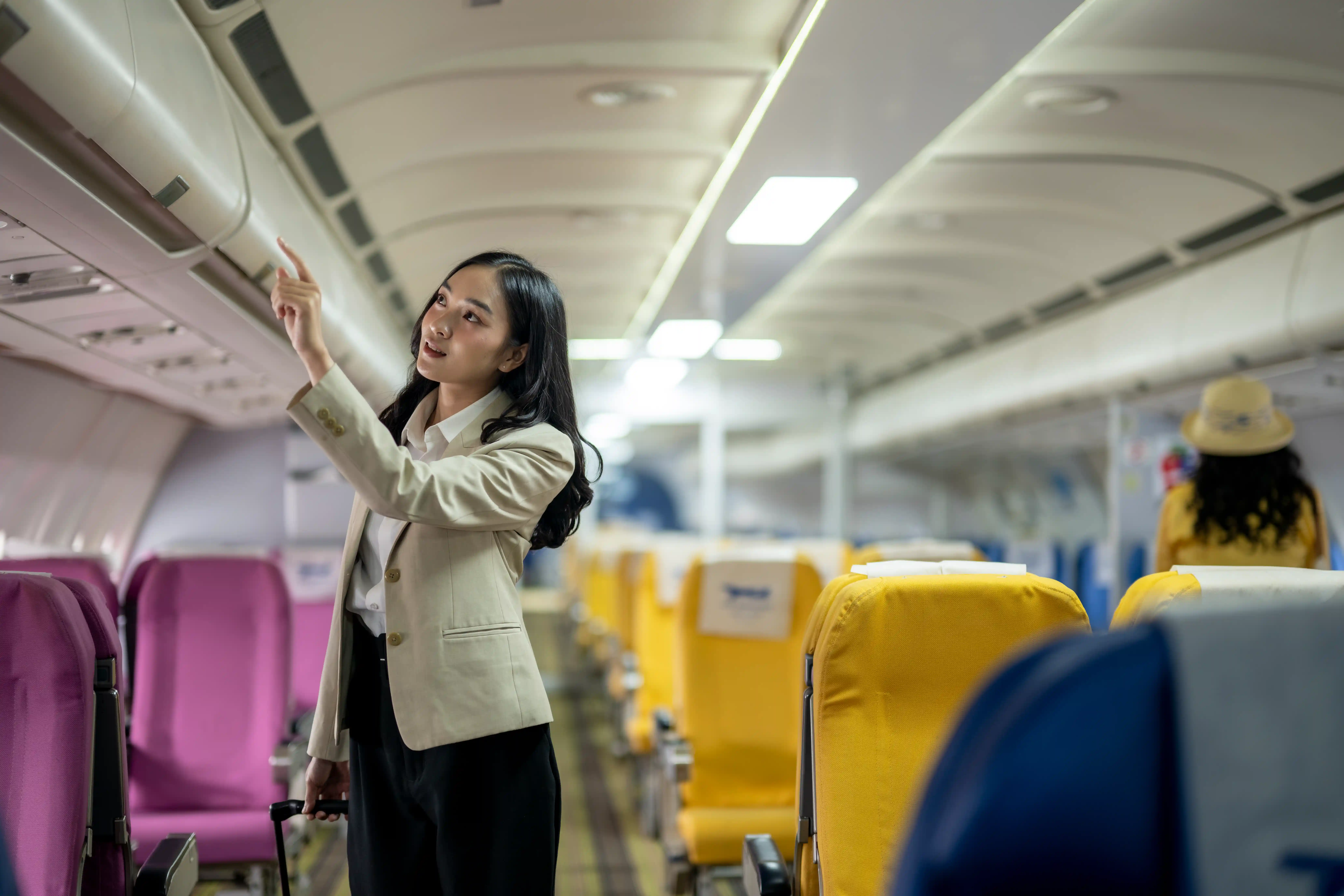 A woman is pointing at a luggage compartment on an airplane