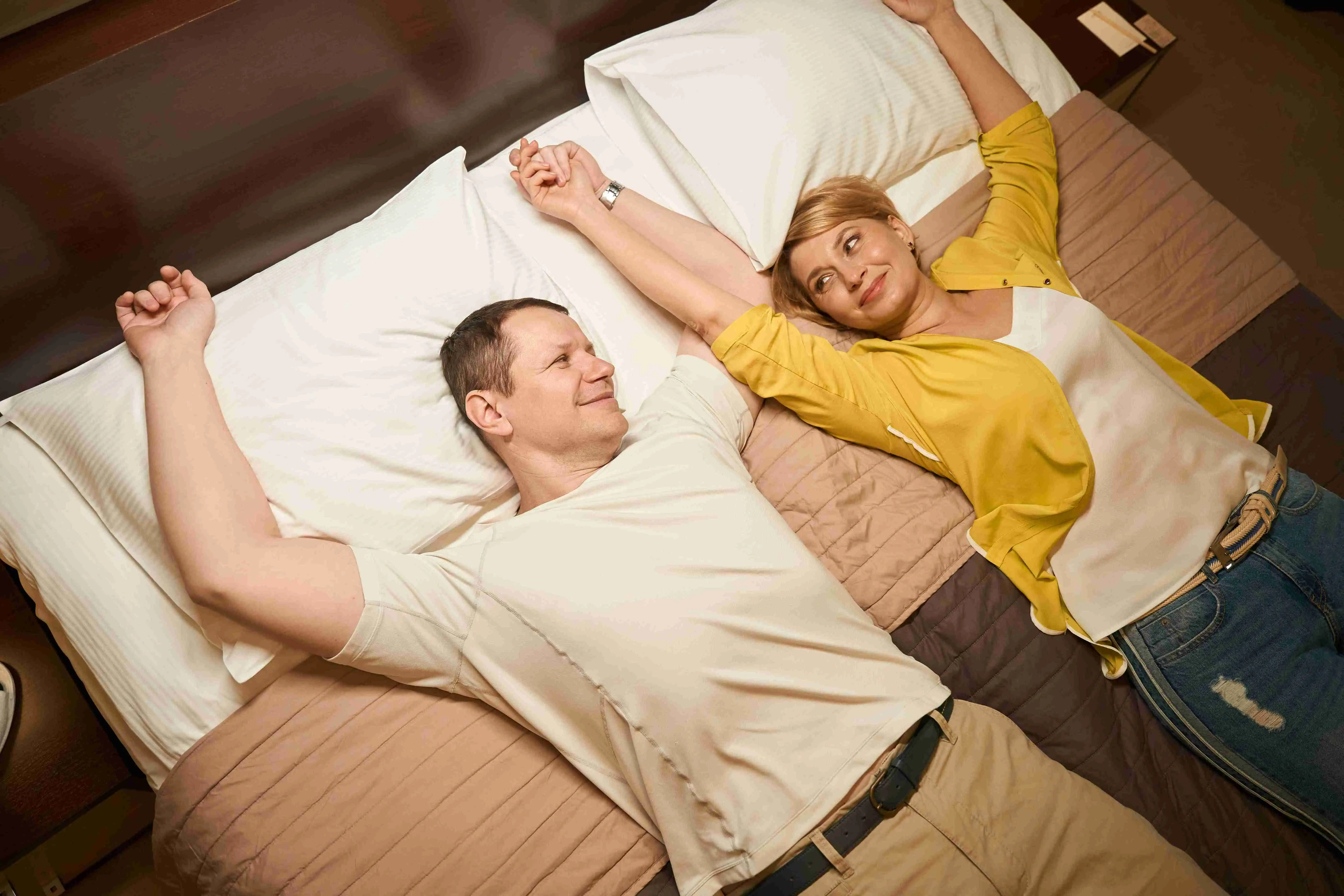 Joyful married couple resting from the road in the bedroom