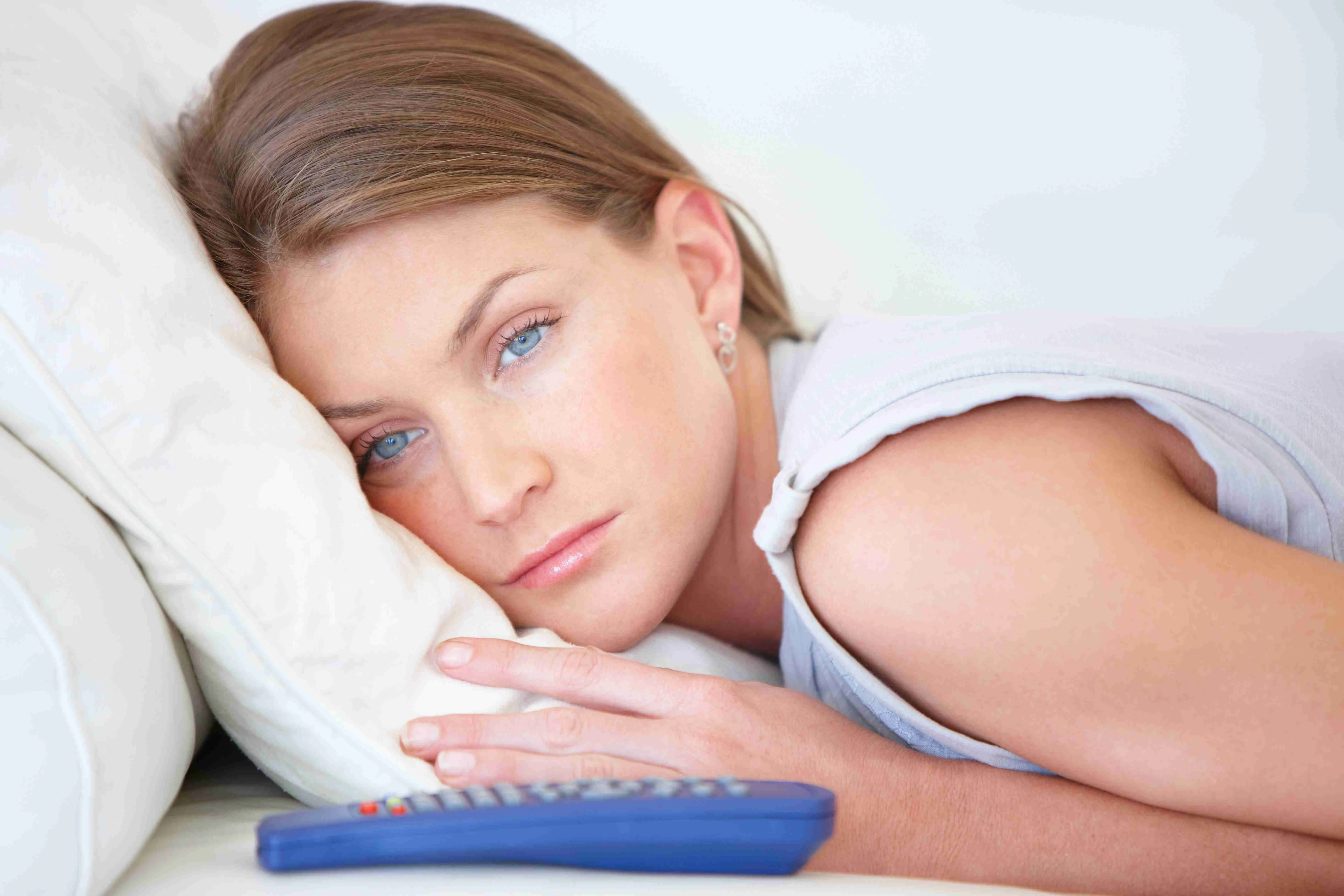 Close-up of a woman lying in bed with a tired expression, looking awake and restless, symbolizing the struggle with insomnia.