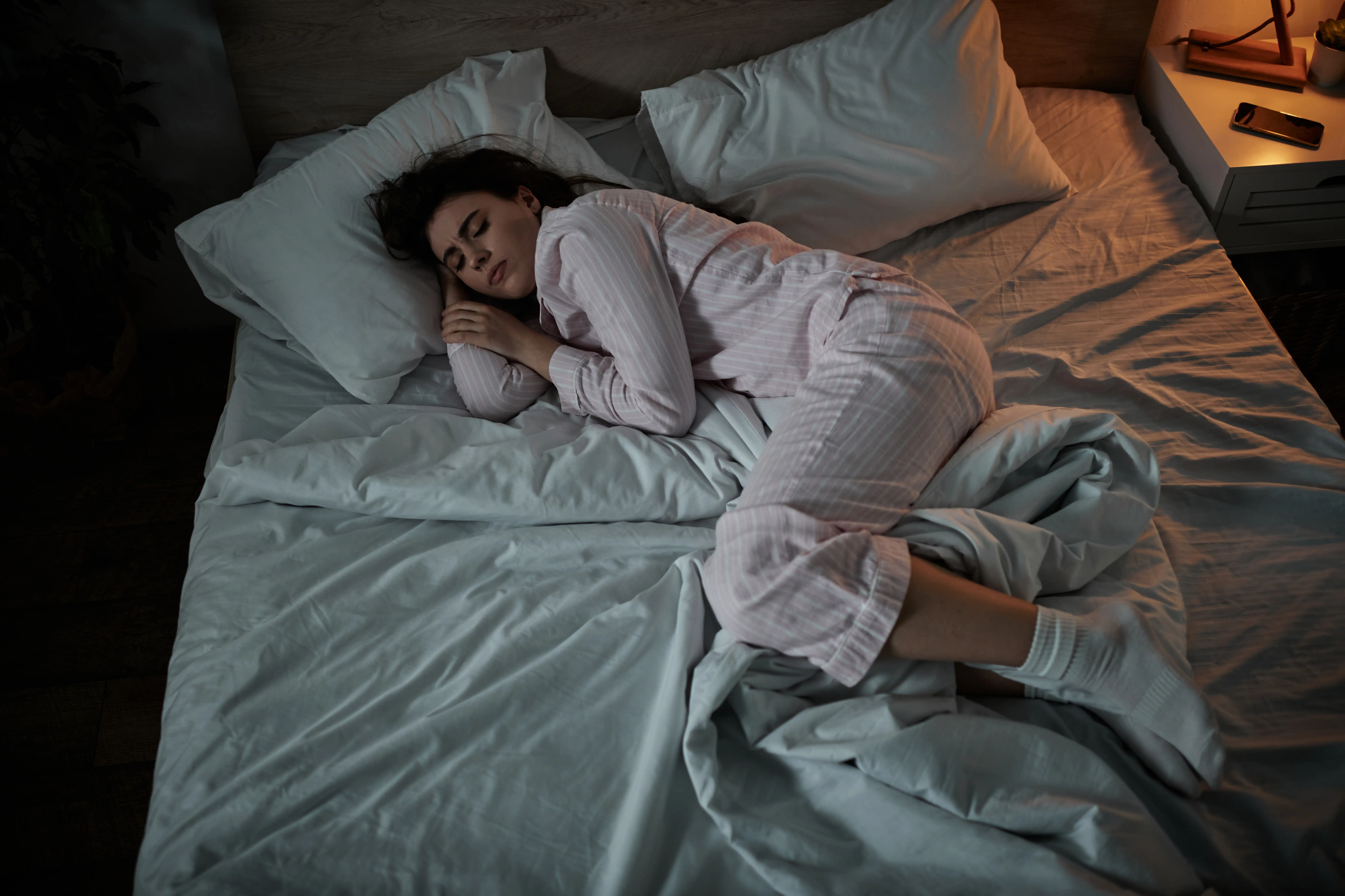 A woman lies curled up in bed