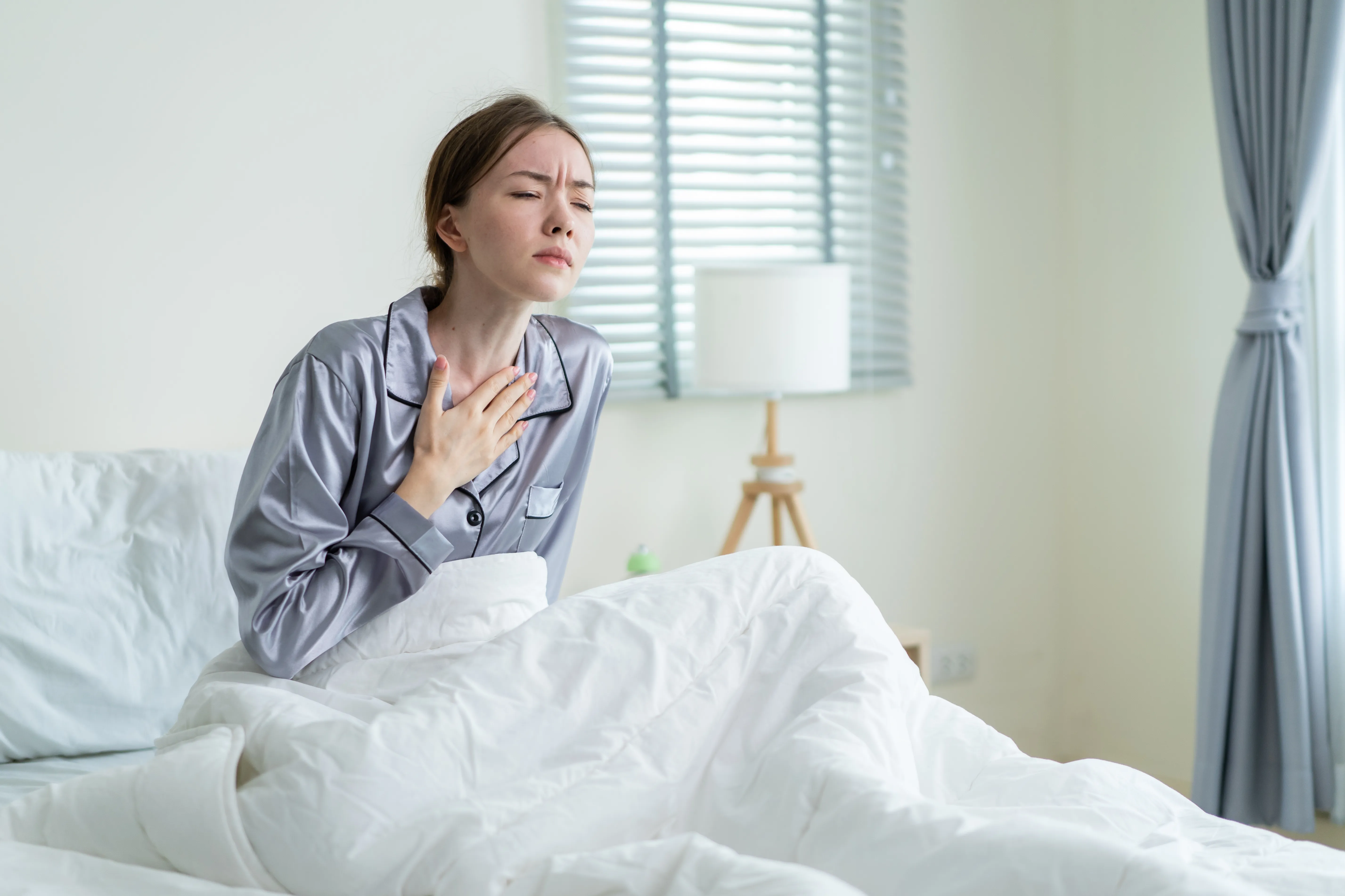 Caucasian beautiful sick girl in pajamas get up from sleep in bedroom.