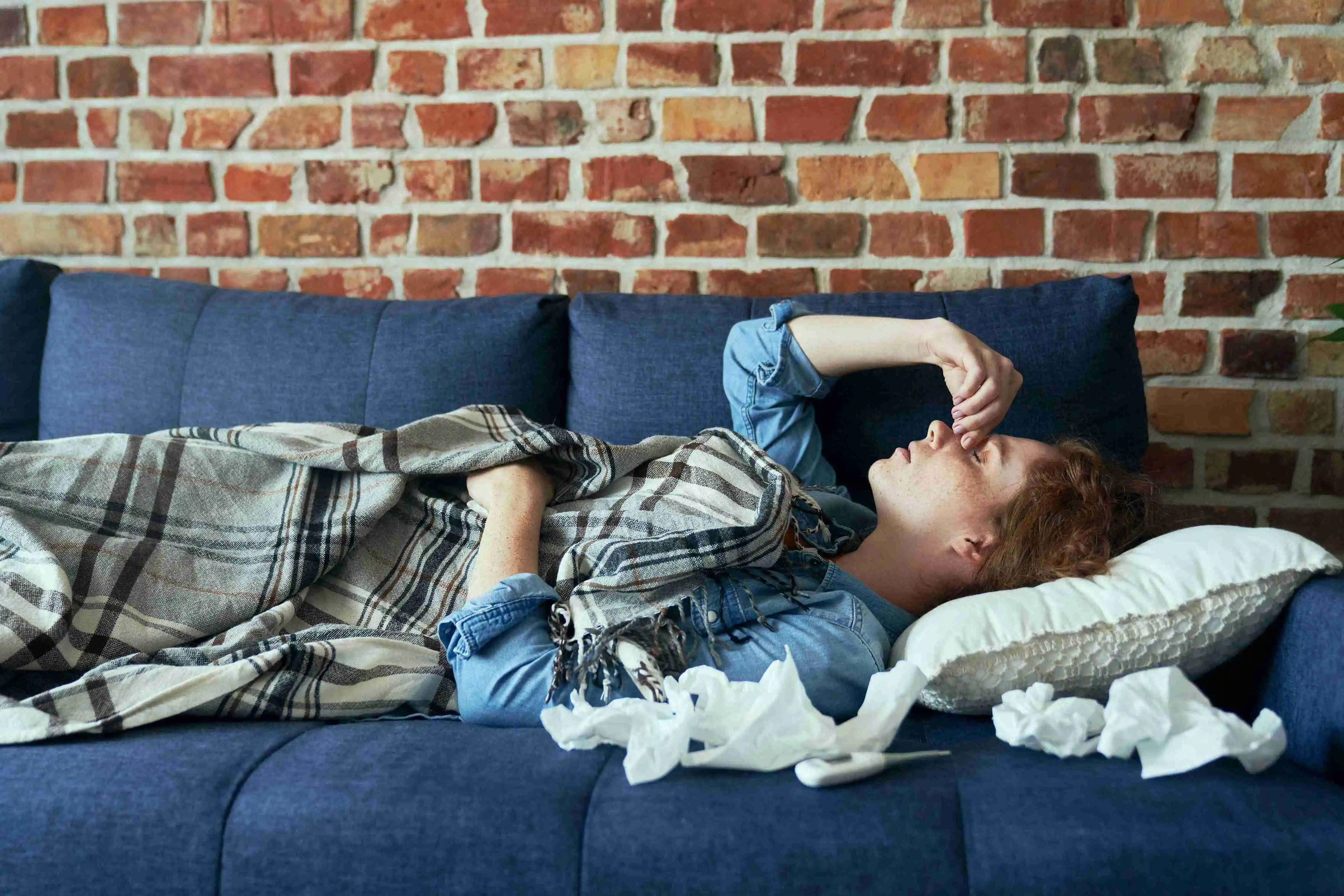 Young Caucasian woman lying on sofa and having a serious sinus infection