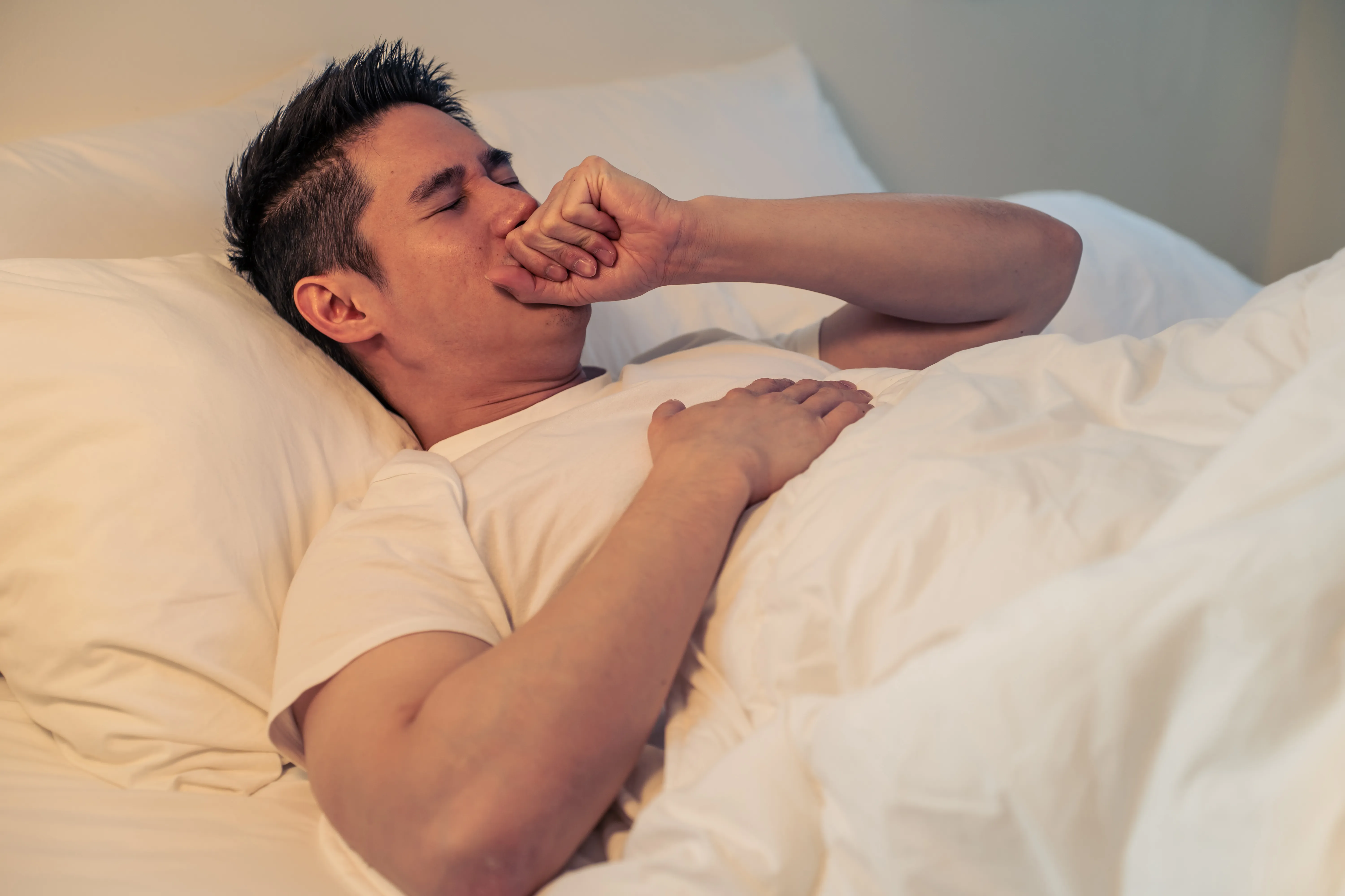 Asian sick handsome male in pajamas sleep in the dark night in bedroom.