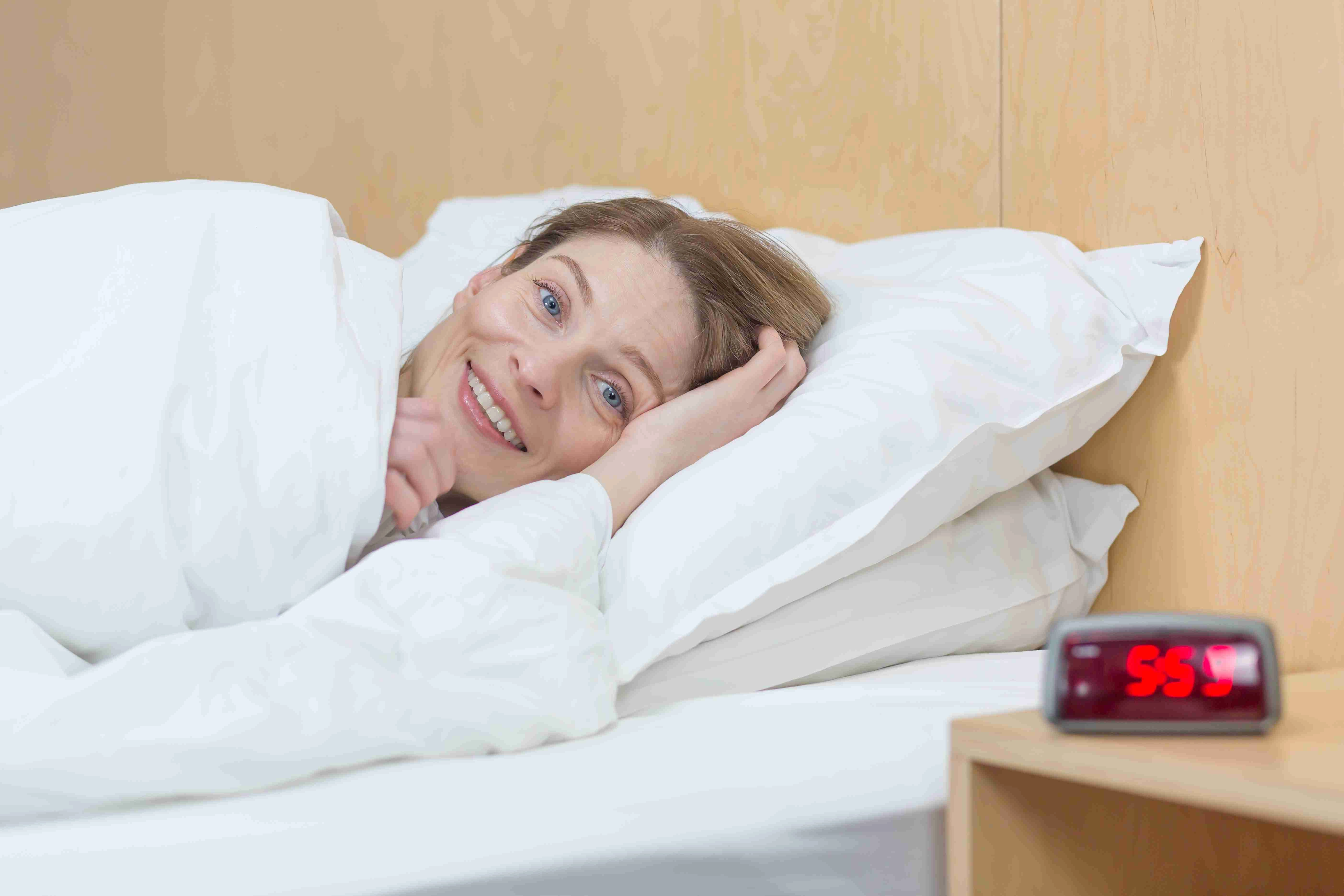 Portrait of a young beautiful woman lying in bed with a white bed