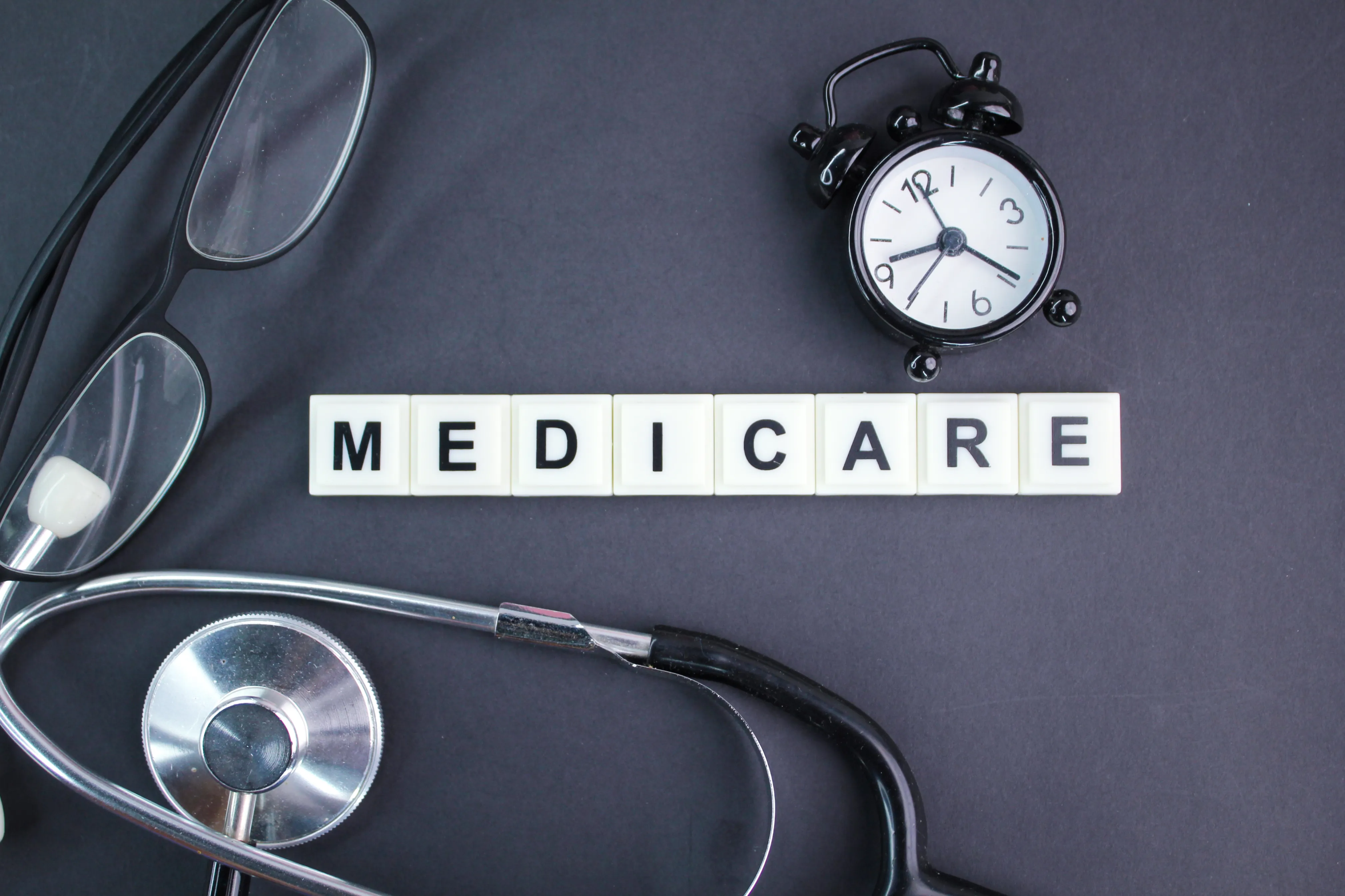 stethoscope, glasses, alarm clock with the alphabet word medicare