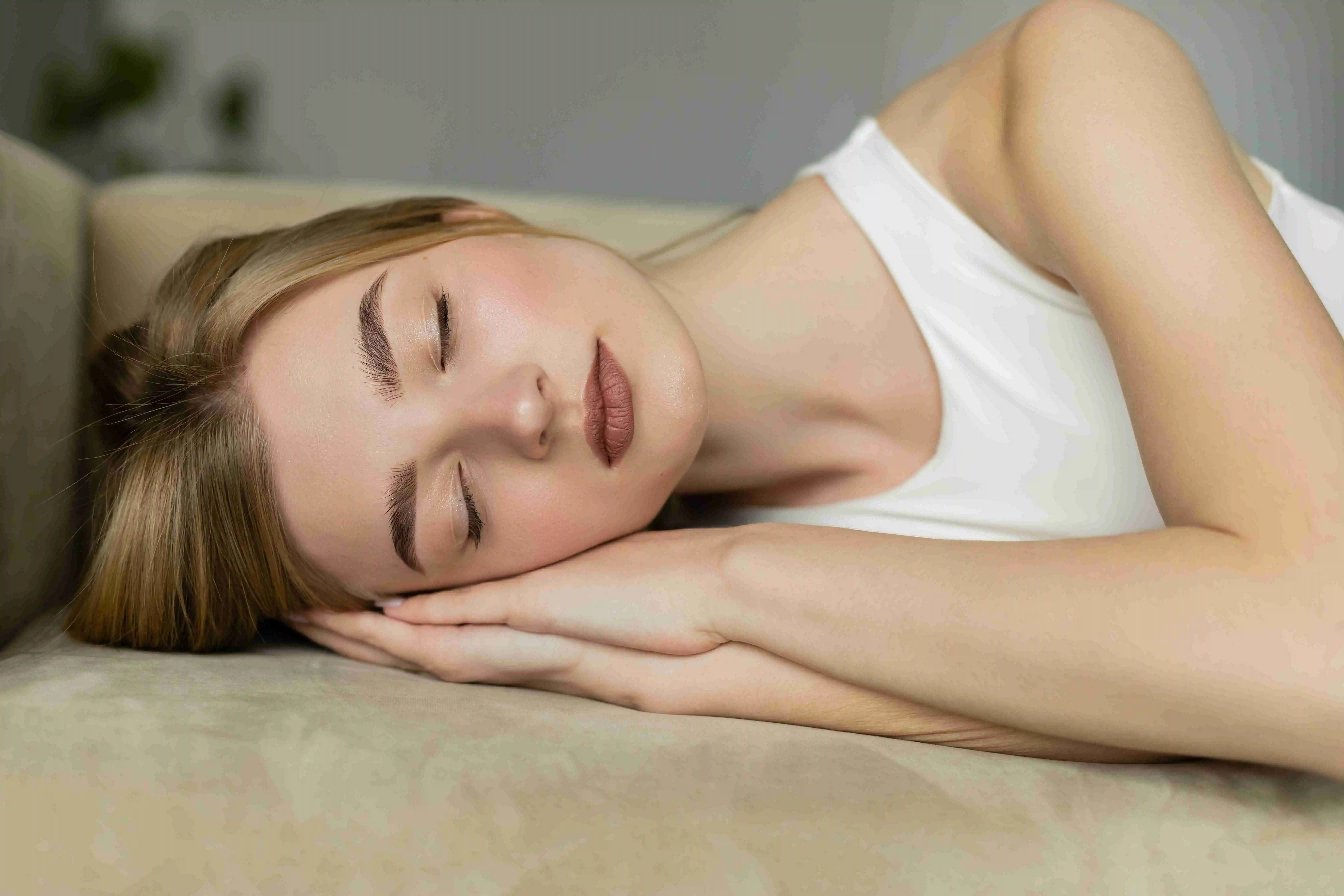 Pretty blonde woman in top sleeping on couch in living room