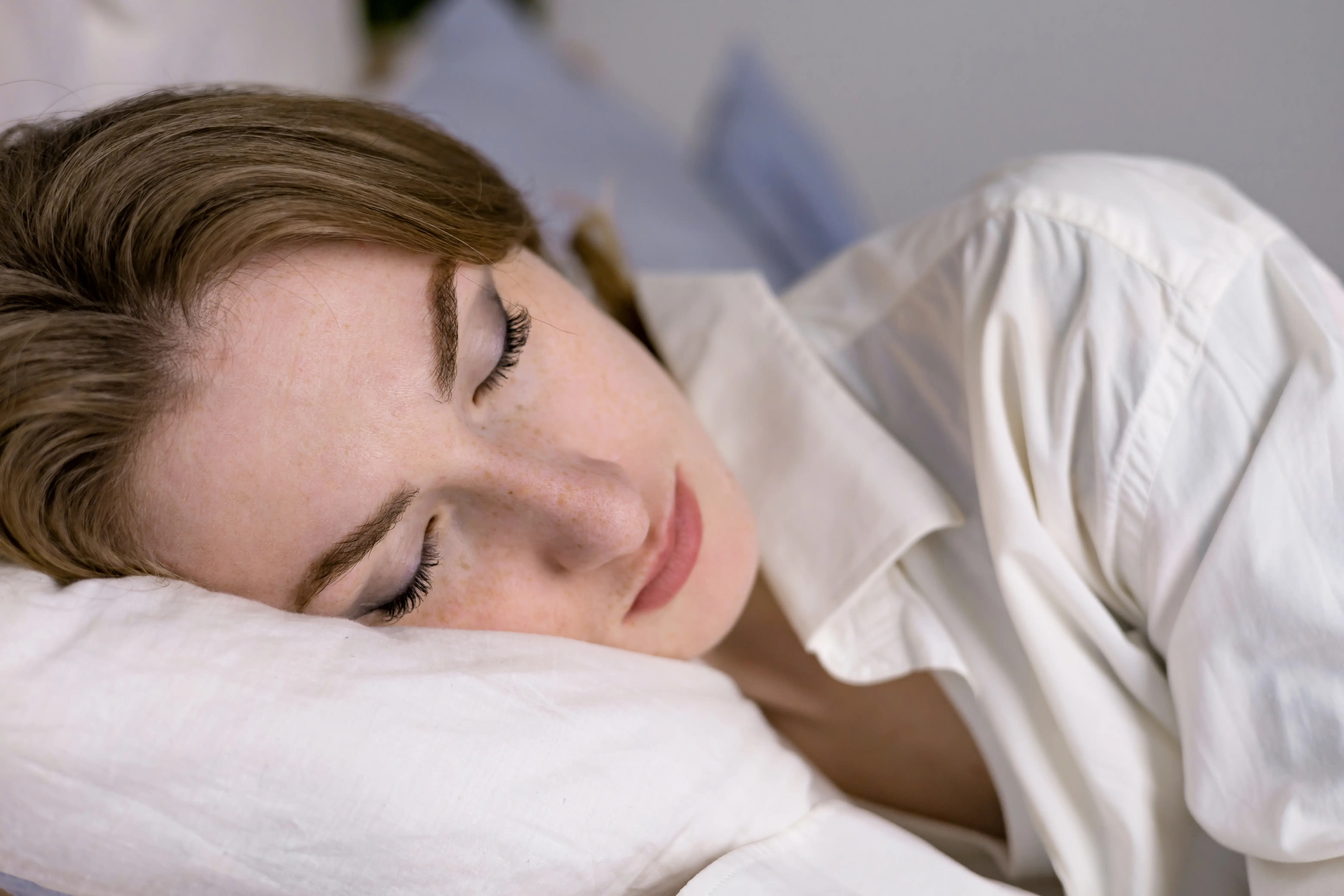 Calm serene beautiful young lady wears pajamas, lying down in a dream