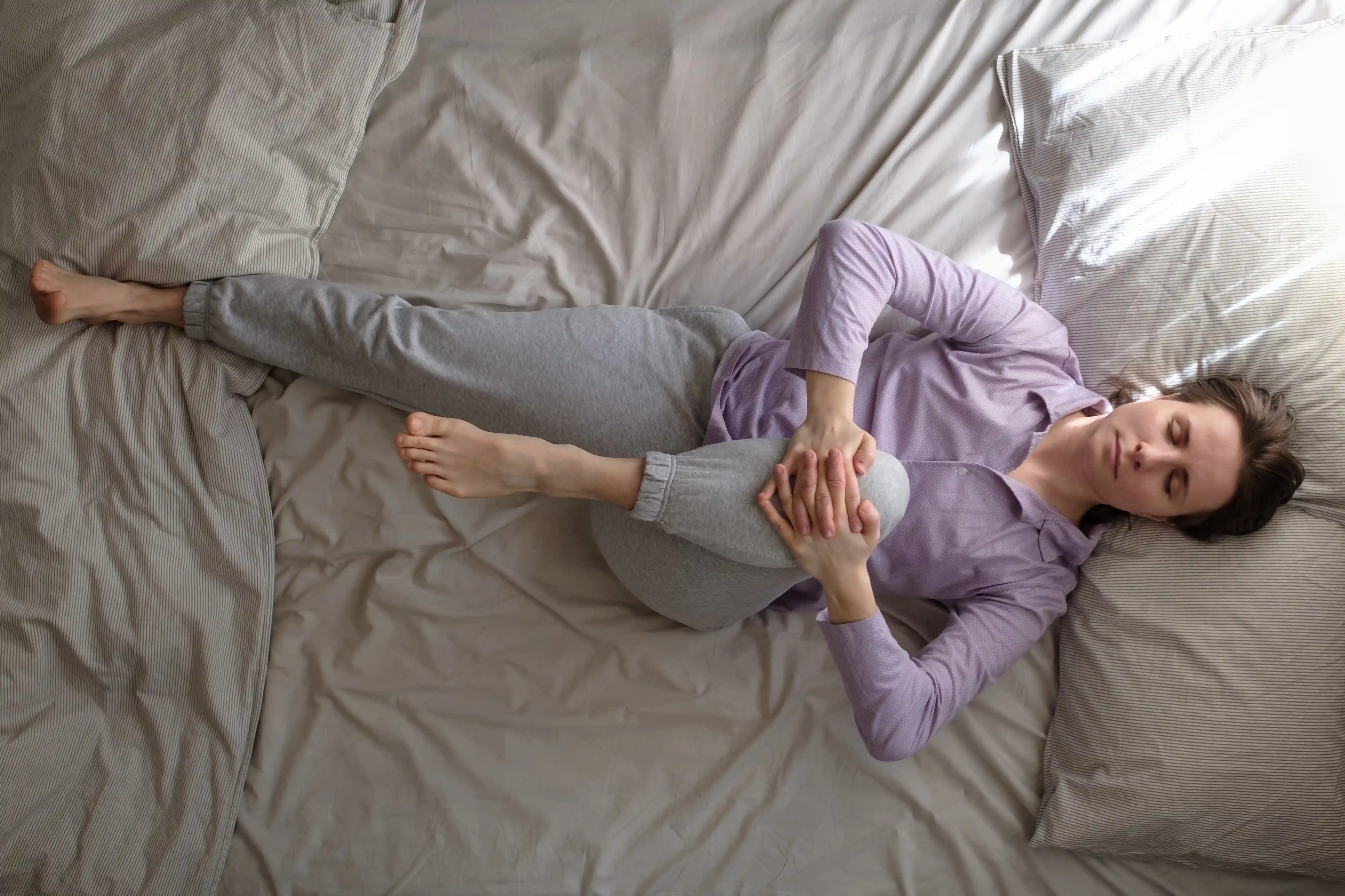 woman lying on bed in the morning and doing stretching exercise from yoga