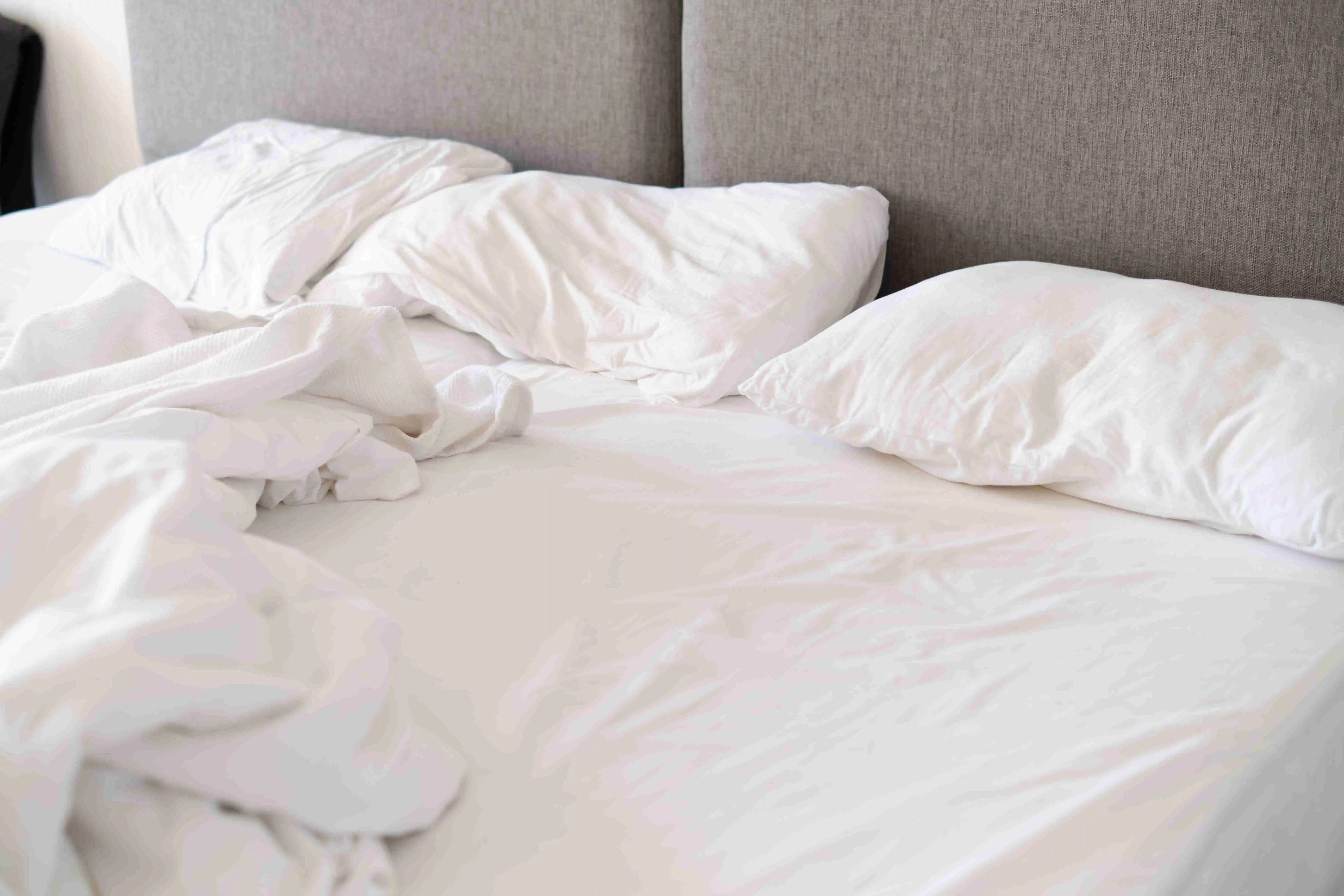 Unmade bed with white linens in soft light, suggesting morning. Speaks to the trend of authenticity