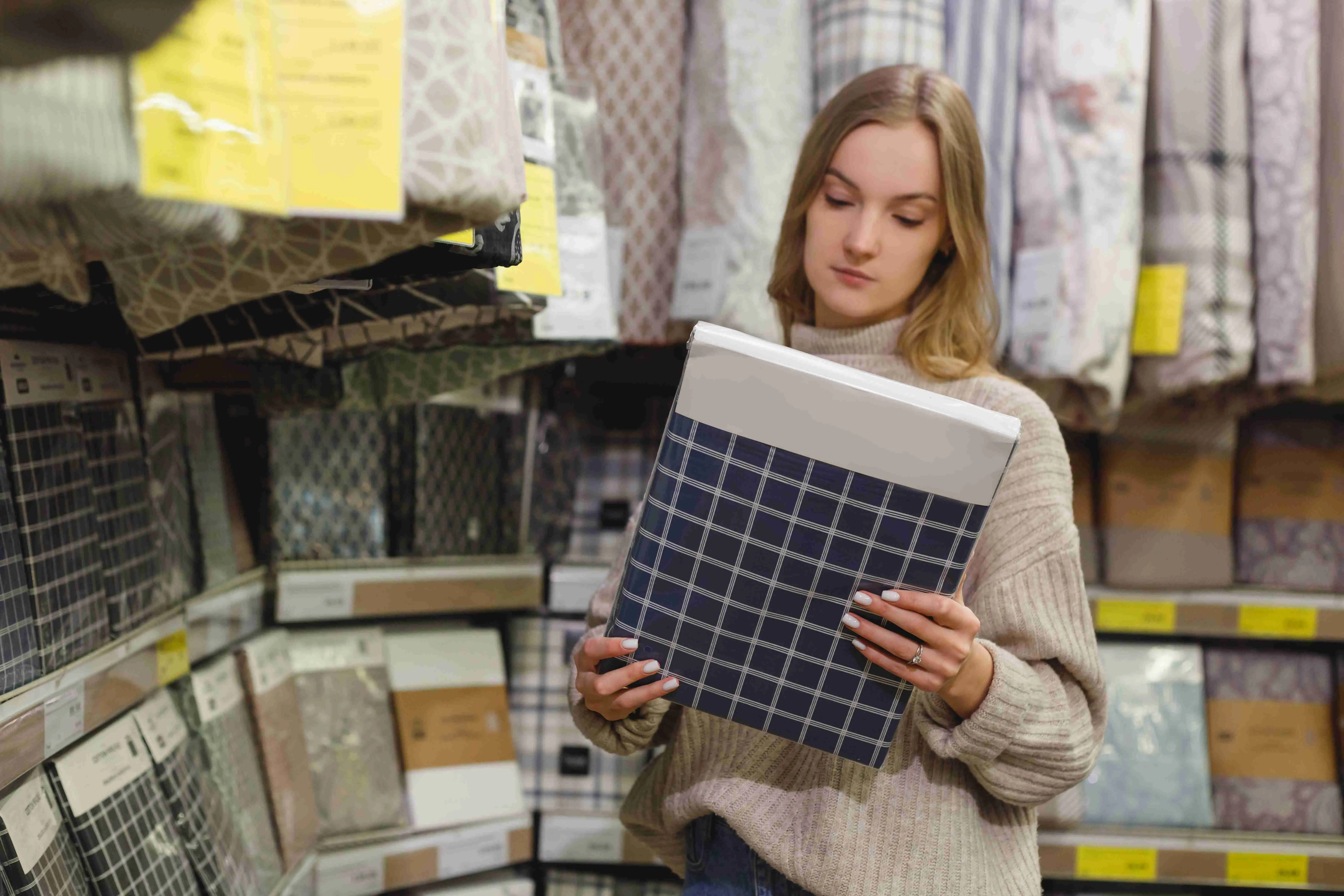 Young cheerful woman choosing Pillowcase in home textile store show room