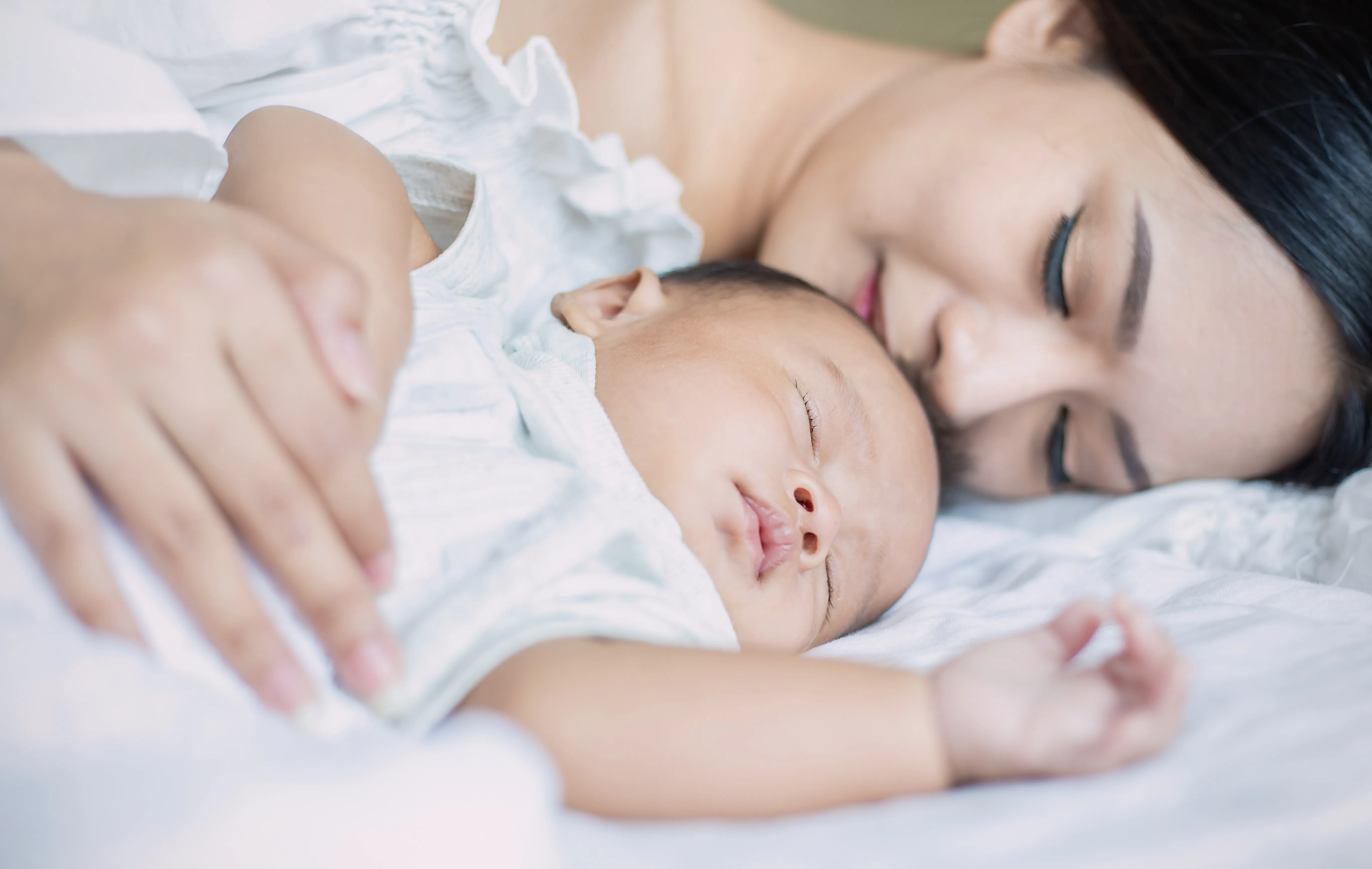 Mother and baby resting comfortably on a white bed