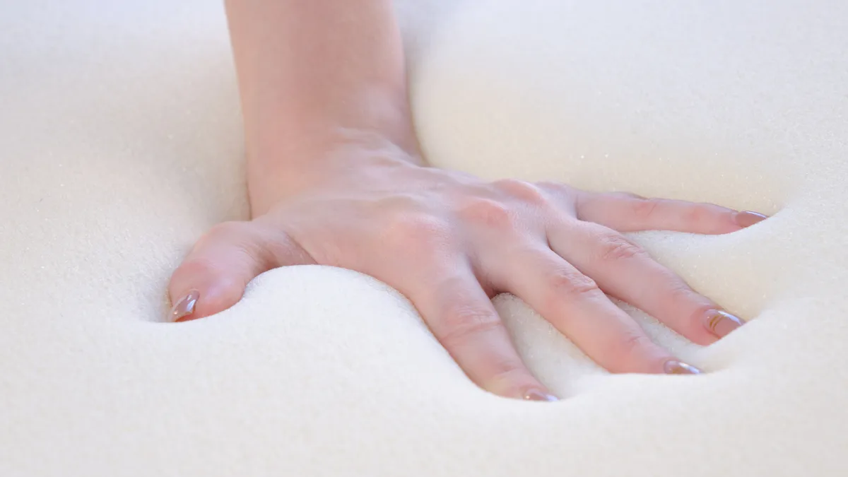 A hand pressing down on a mattress to test its firmness
