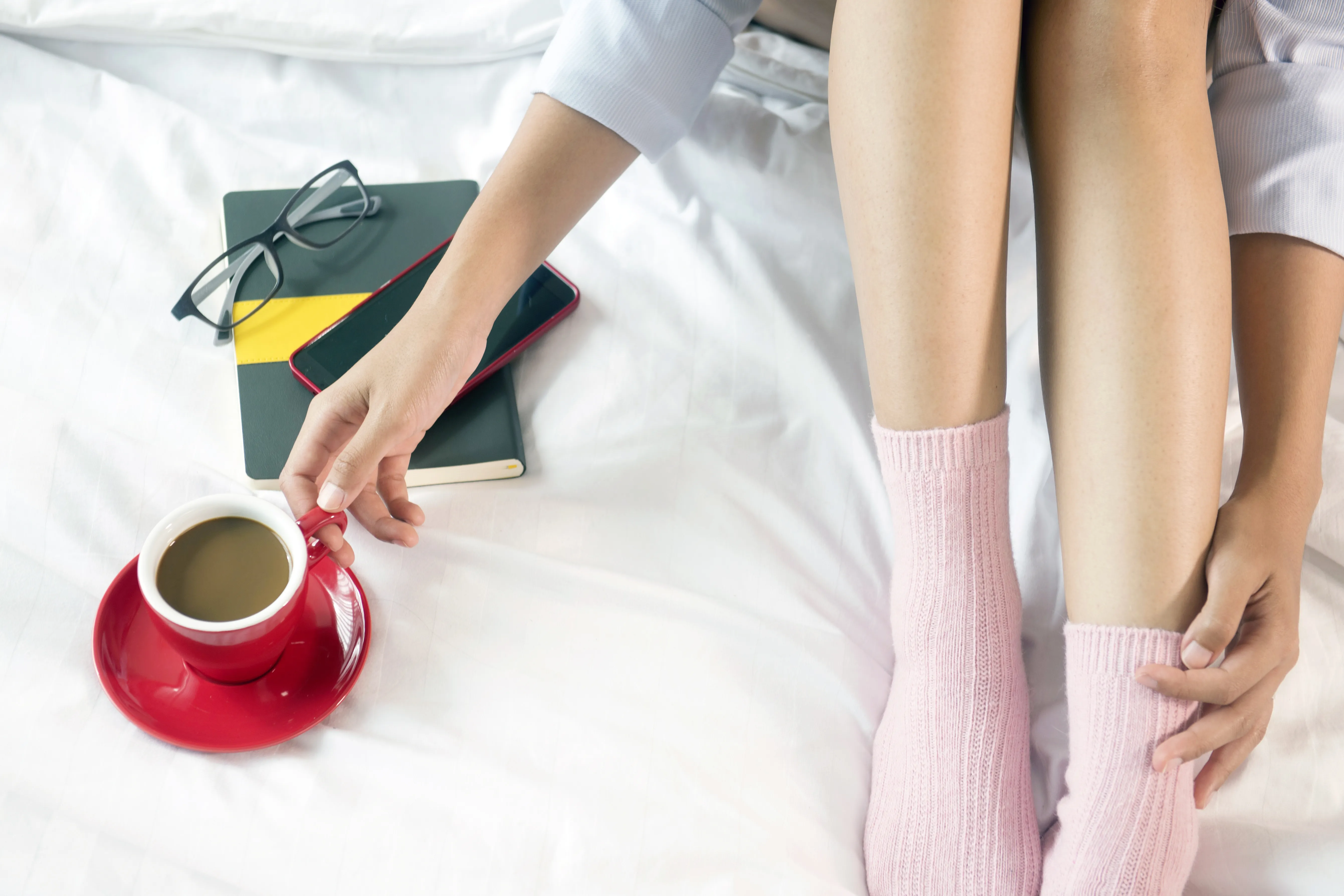 Woman sitting on a bed while holding a cup of coffee