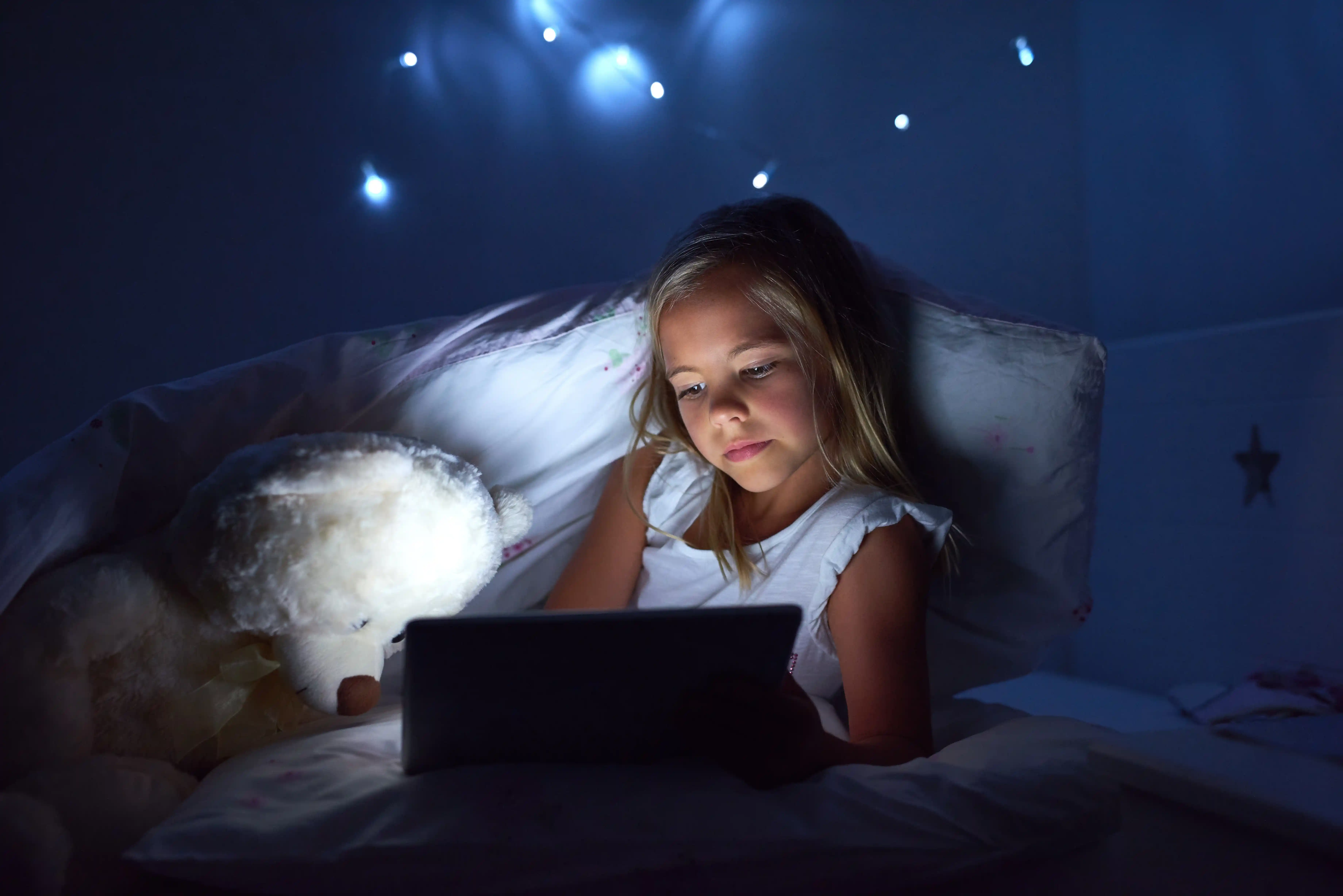 Child using a tablet in bed before sleep