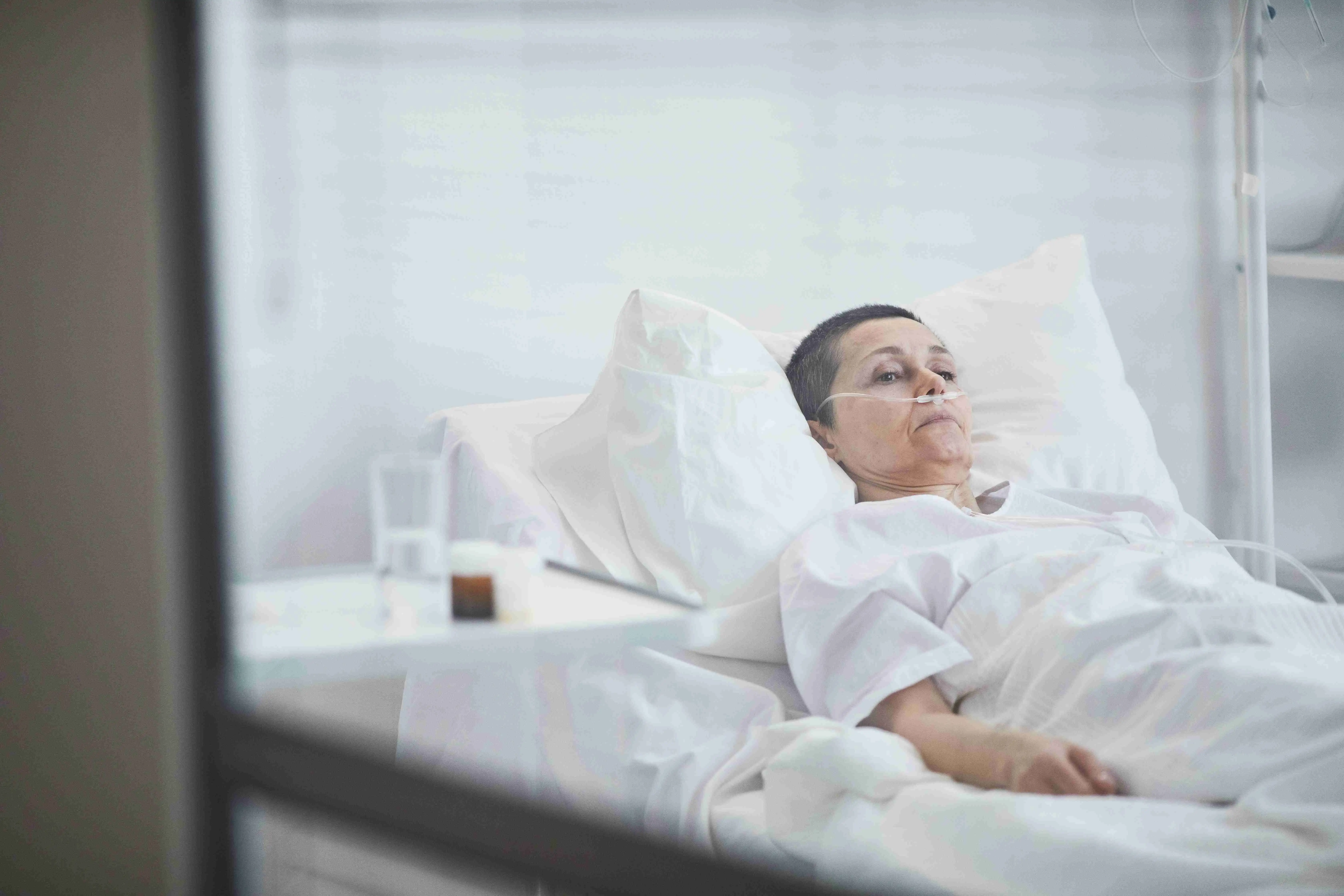 Mature woman lying on hospital bed under dropper at hospital