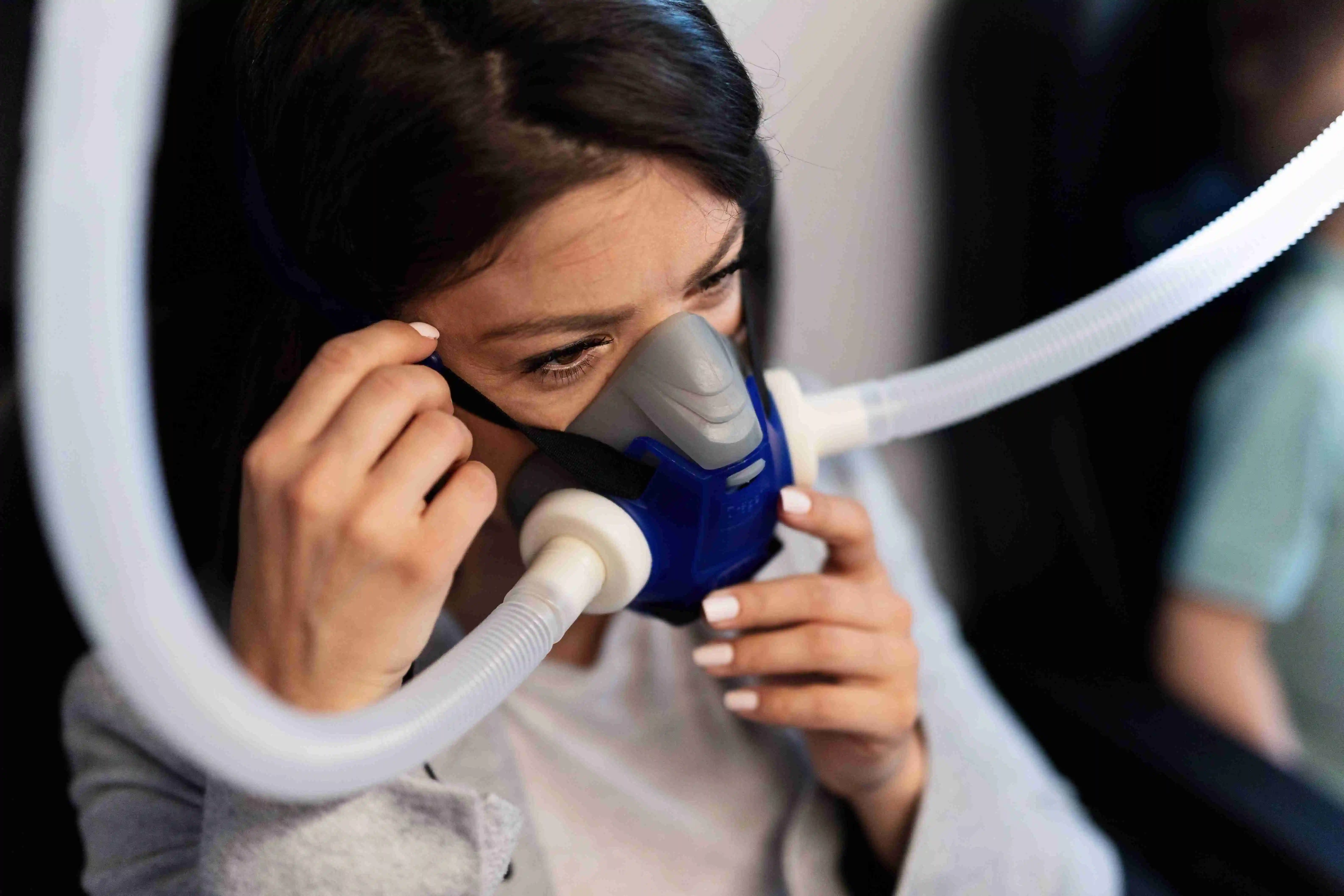 Woman adjusting mask during CPAP therapy.