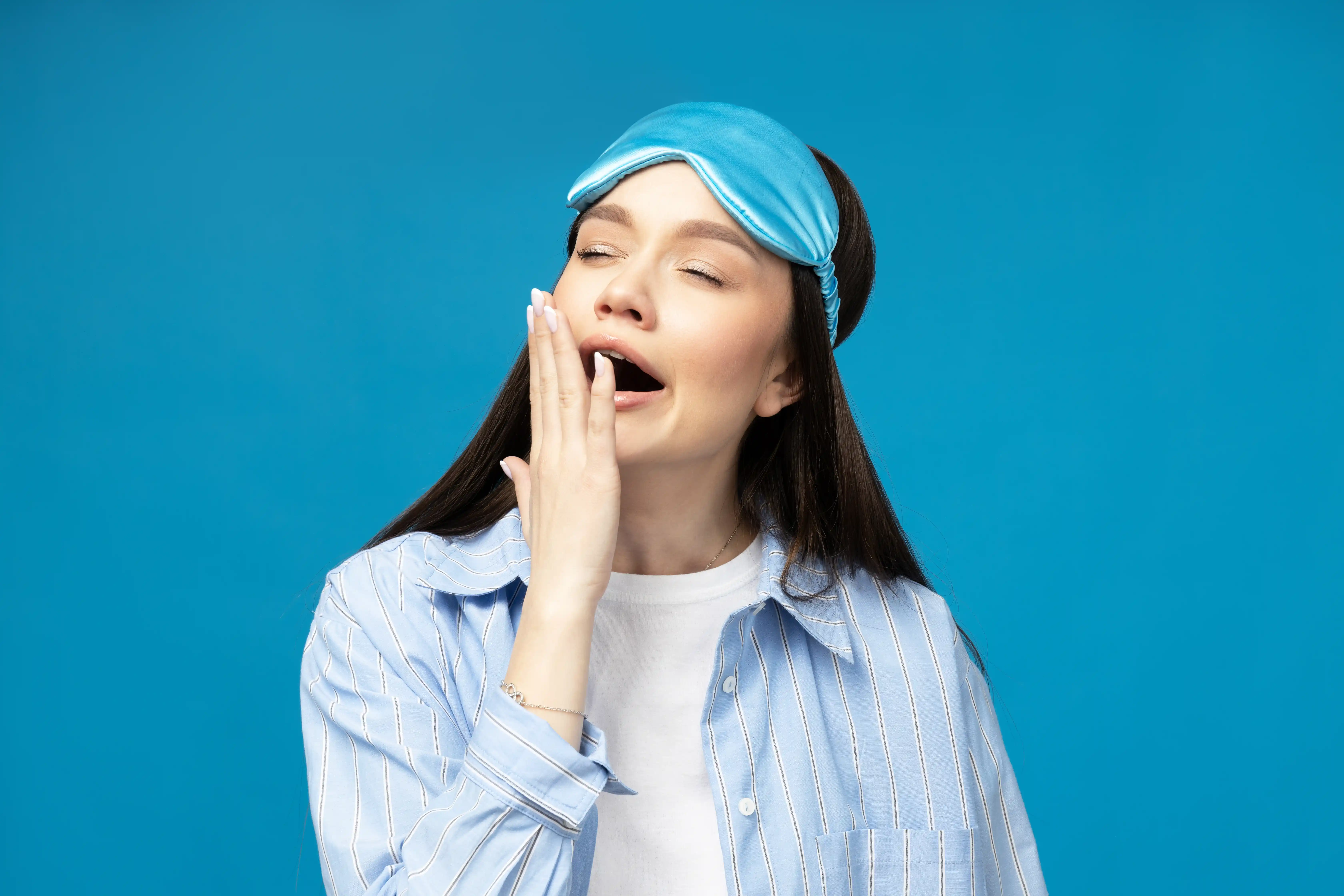 Young woman in a sleeping mask on a blue background