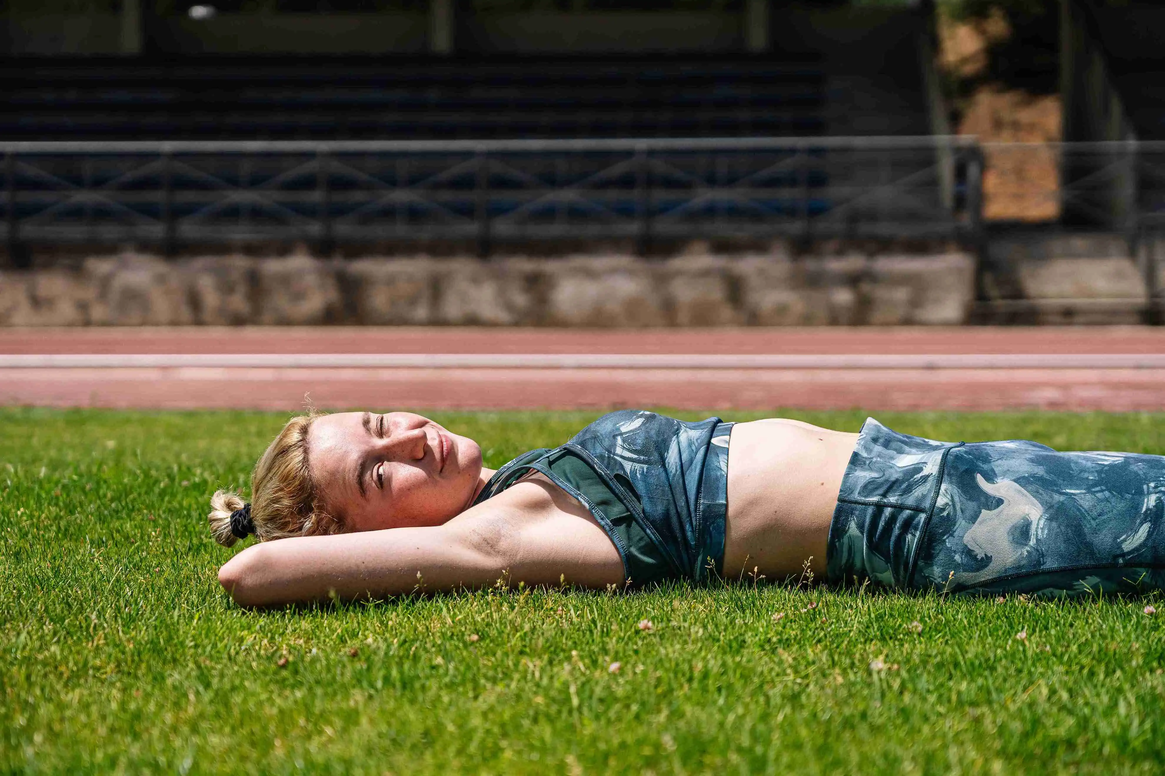 Calm sportswoman lying on grass during break