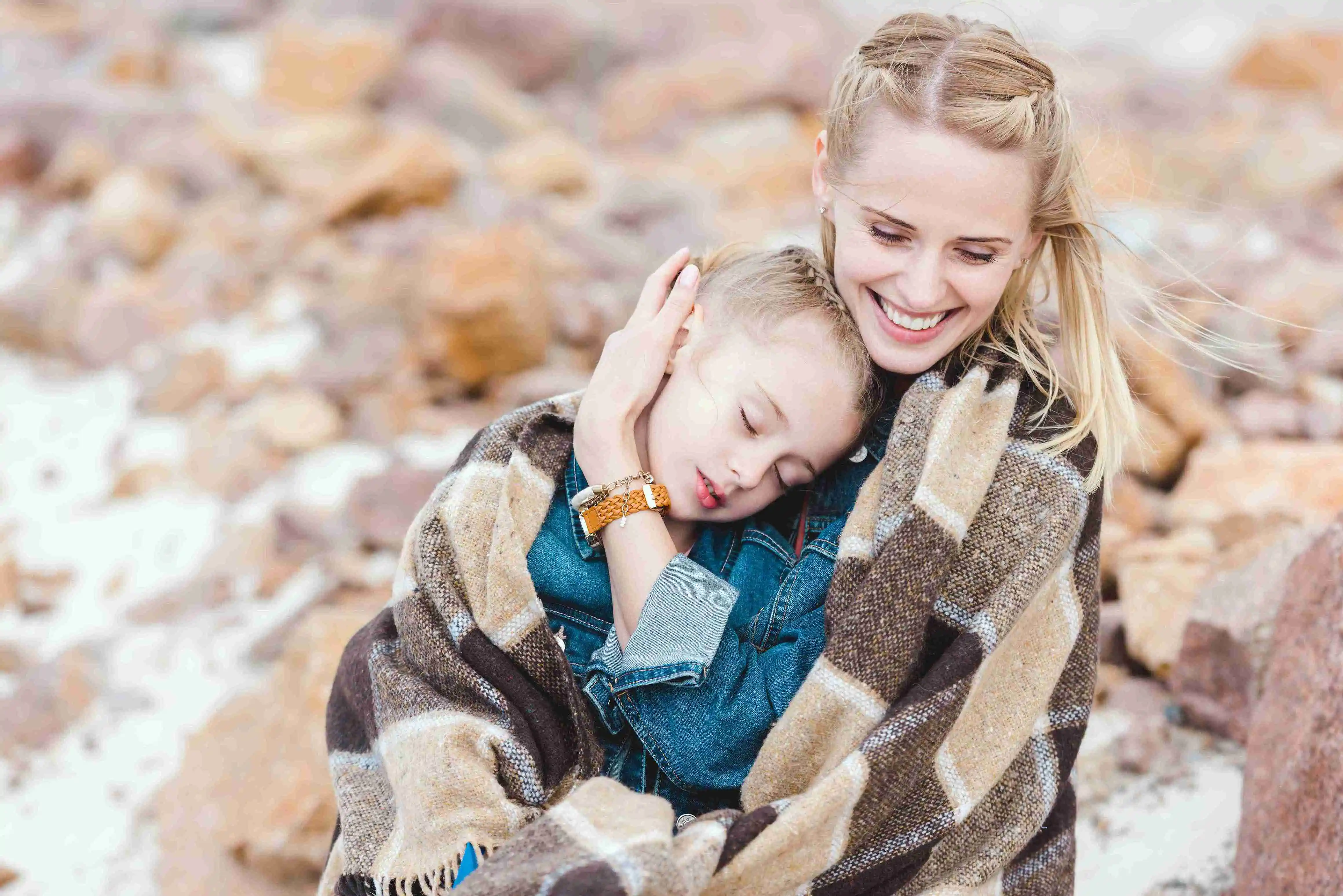 smiling mother hugging her adorable sleeping daughter in blanket