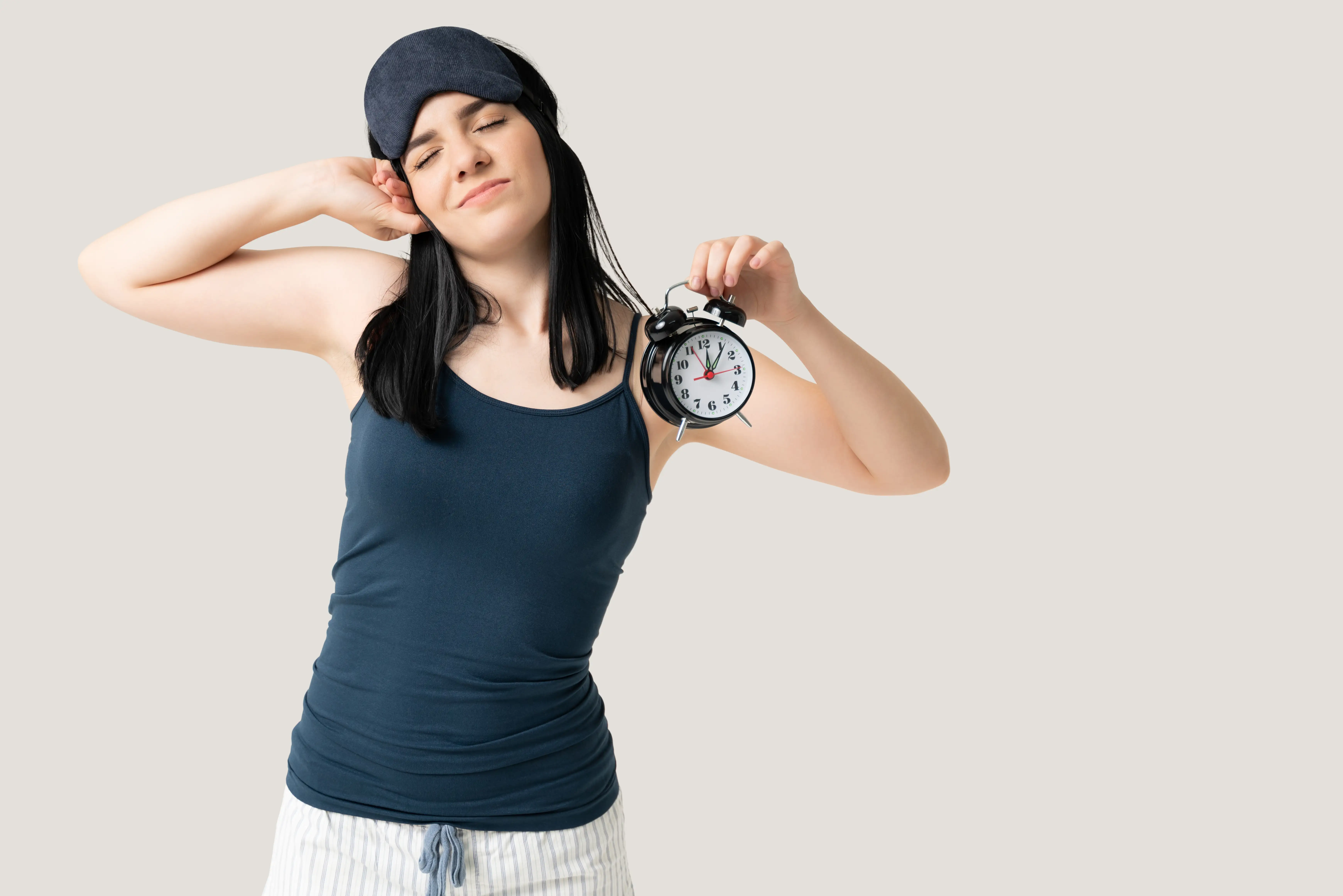 Woman With Sleeping Mask Holding Alarm Clock