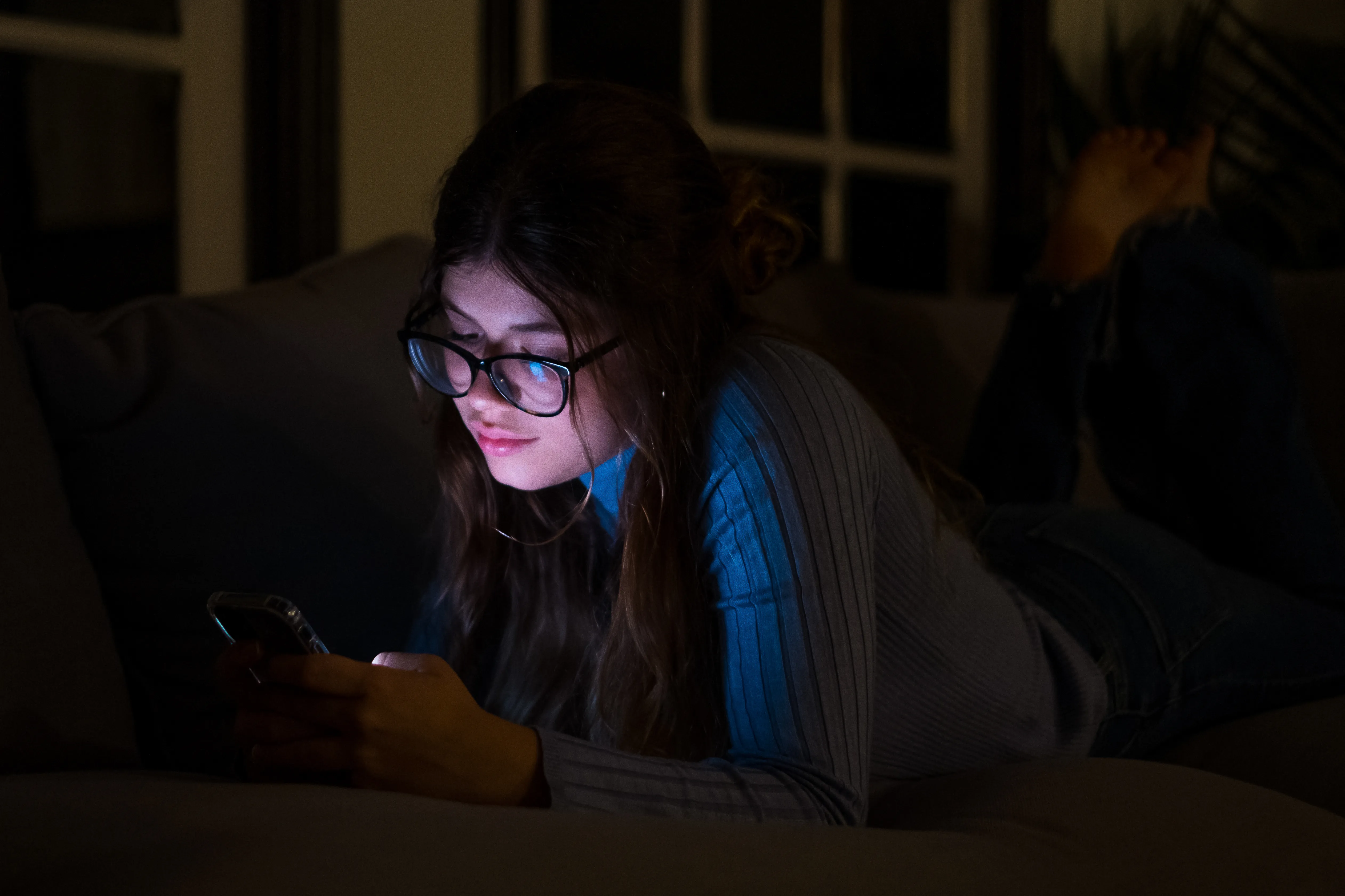 One happy and insomniac woman using phone late at night in the bedroom at home chatting.