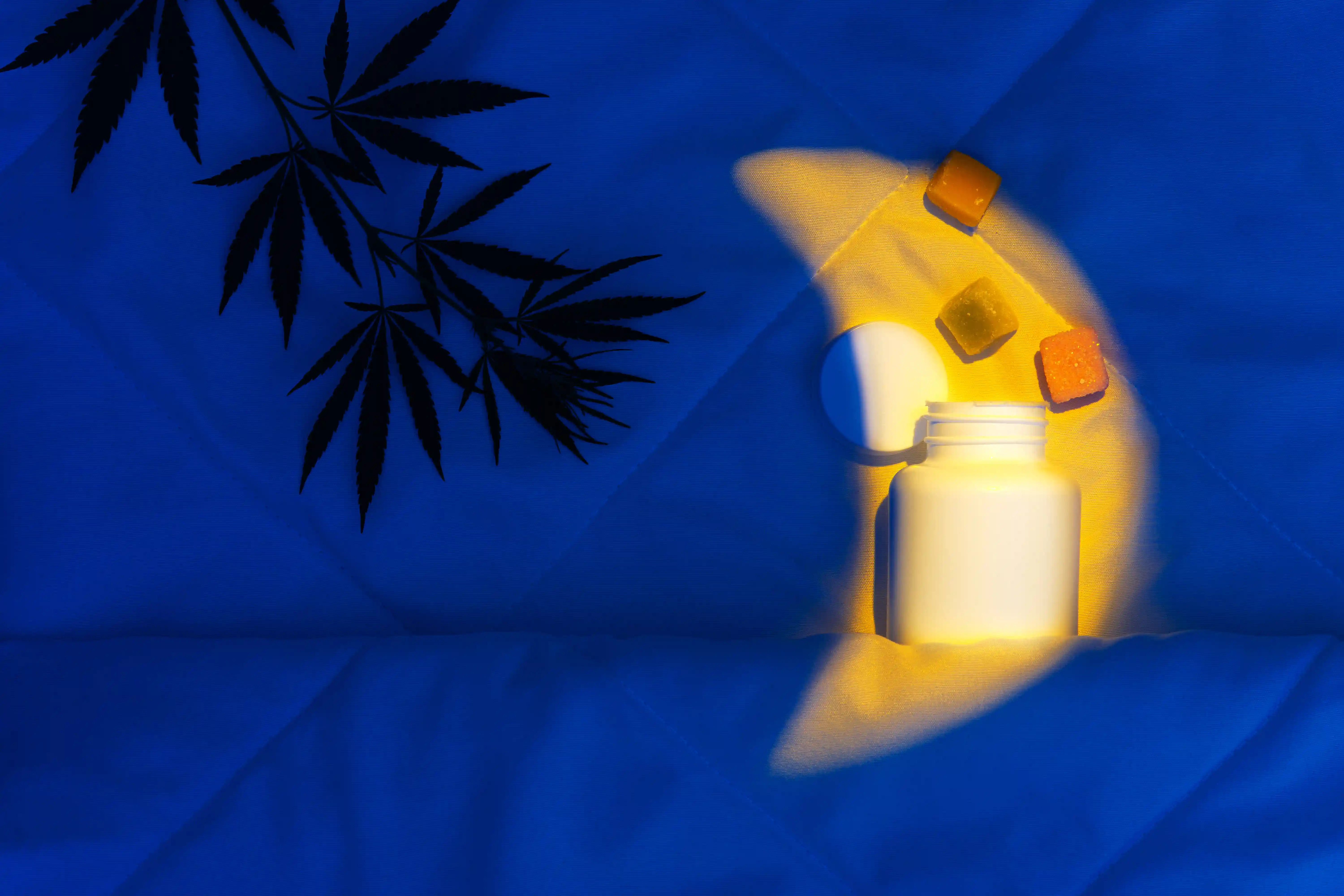 Sleep supplement gummies in a container beside a bed