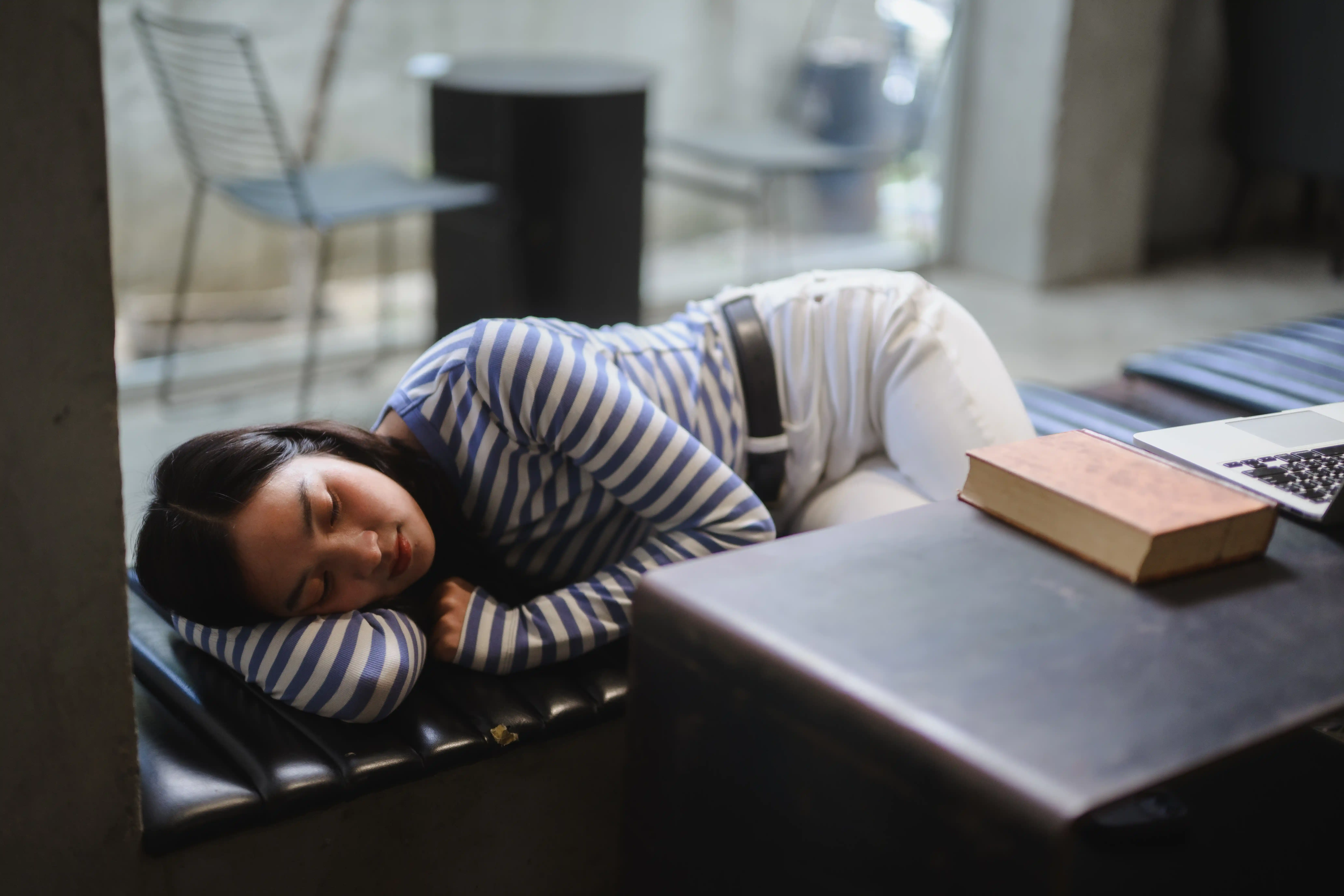 Student resting beside a laptop and book in a university library