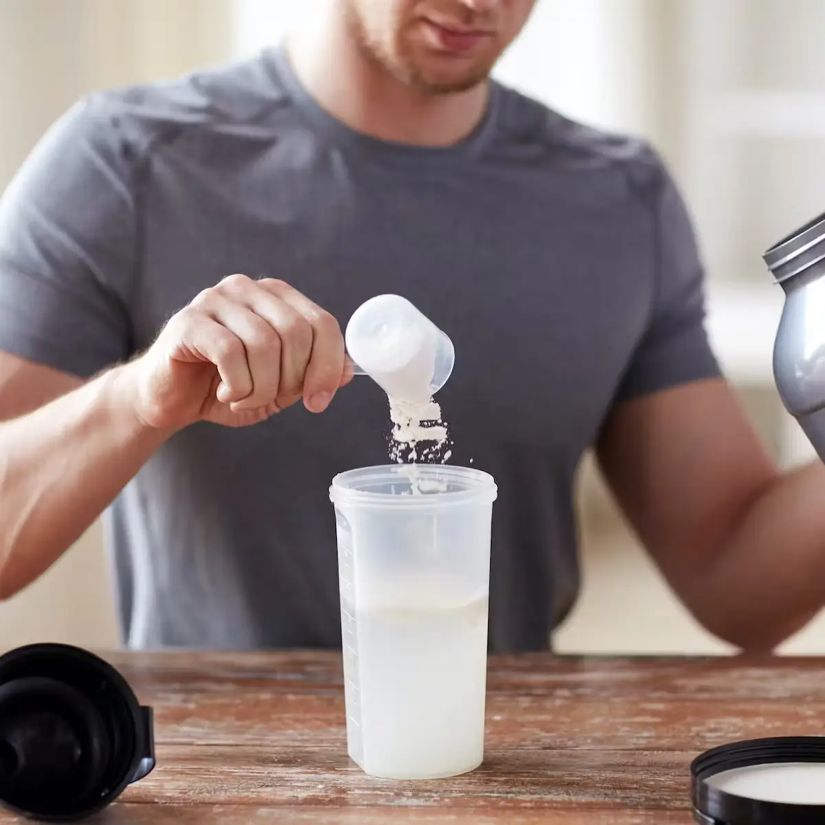 A man putting creatine scoop in shaker 