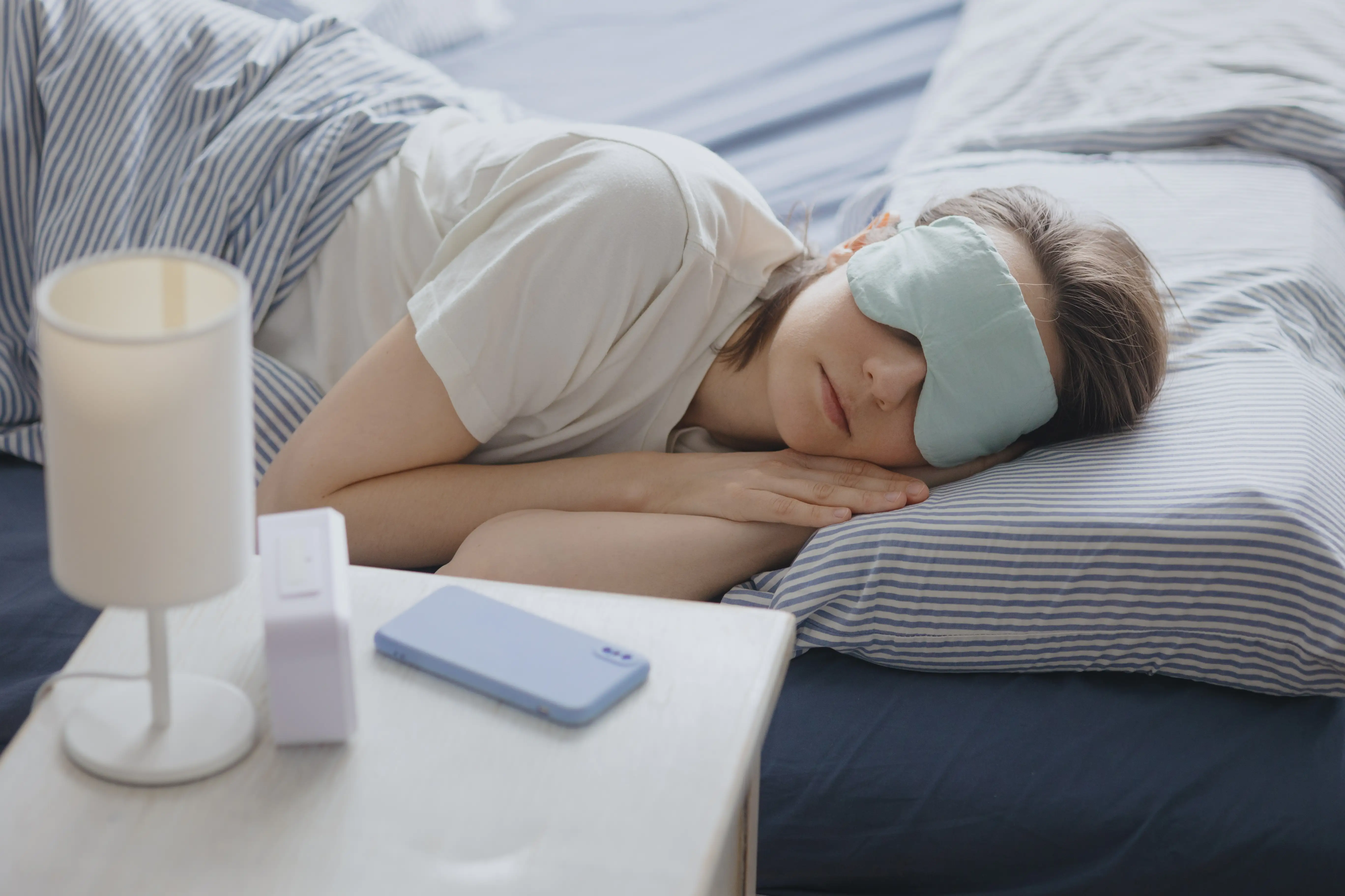 woman sleeps in bed wearing a sleep mask