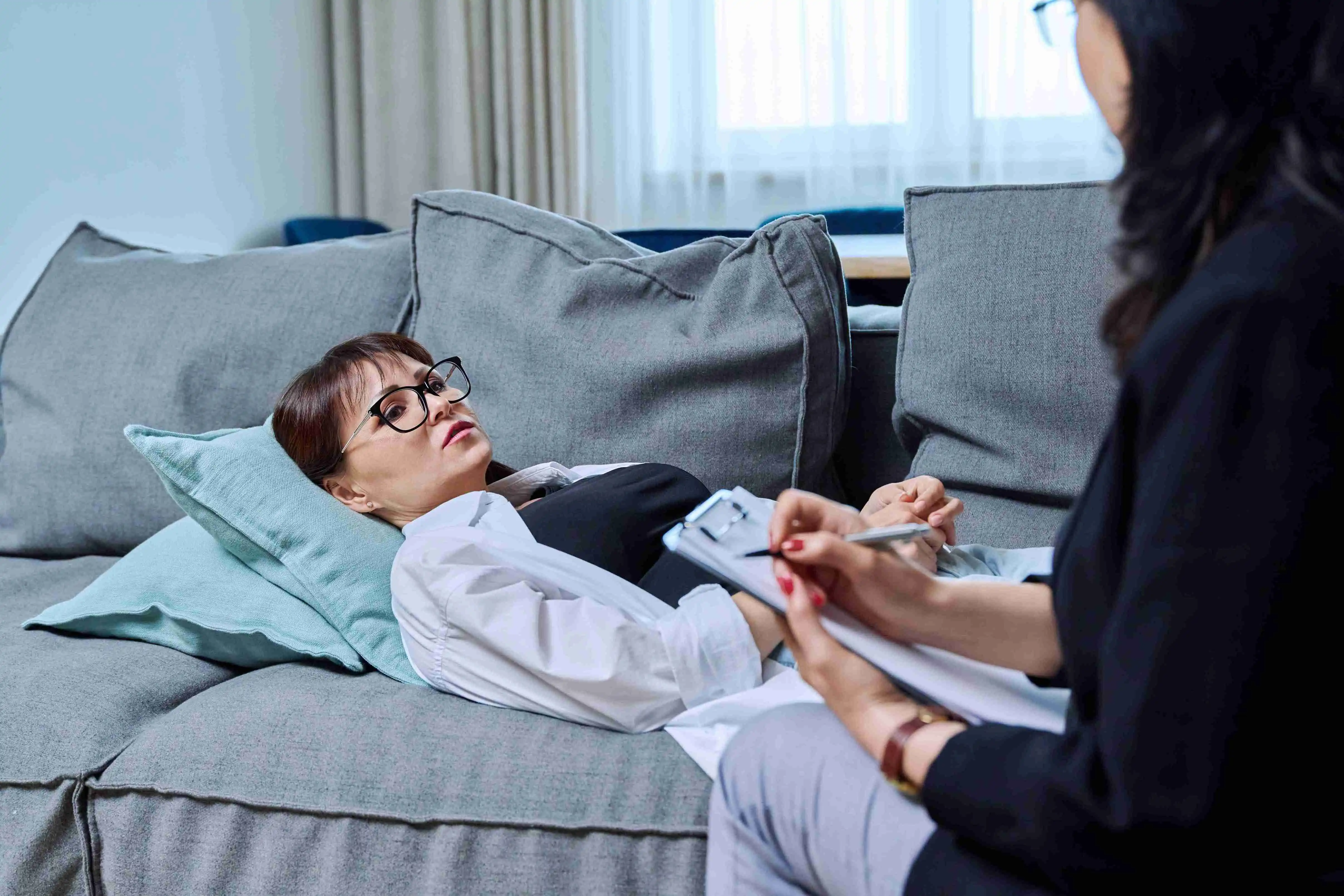 Female psychologist having therapy with middle-aged woman patient in office