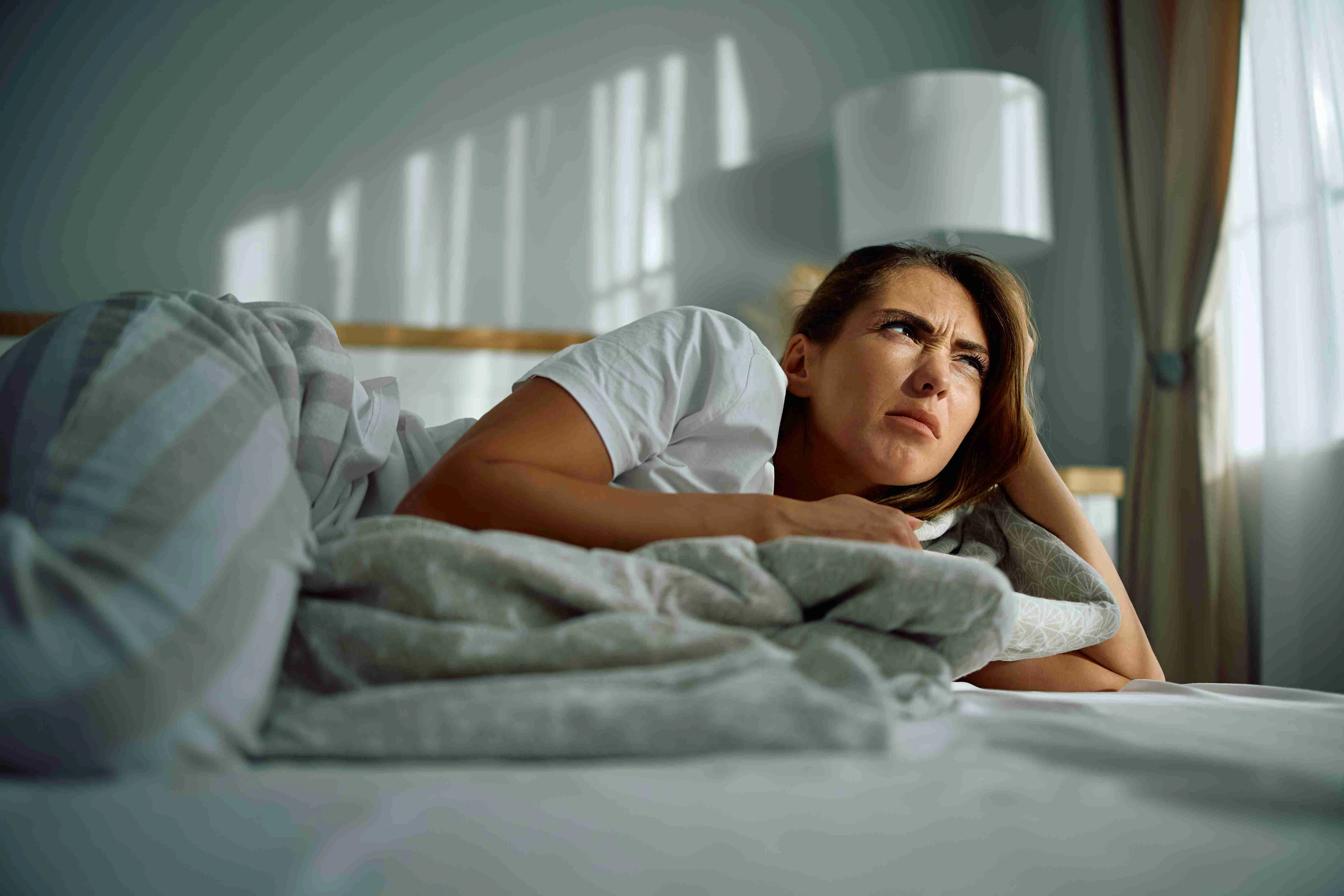 Young cranky woman lying in bedroom in the morning.