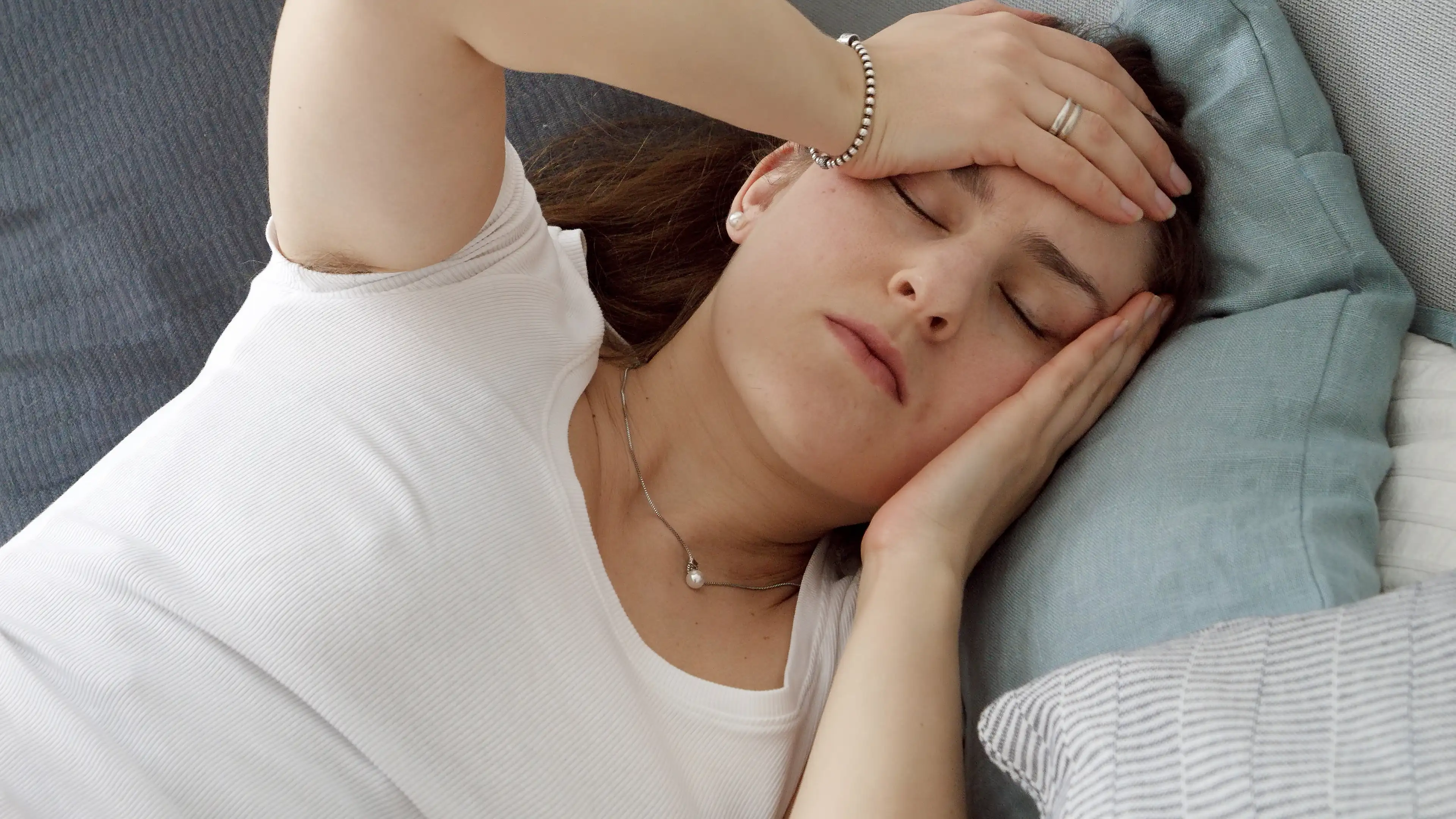 Portrait of tired or stressed woman lying on bed and suffering from headache