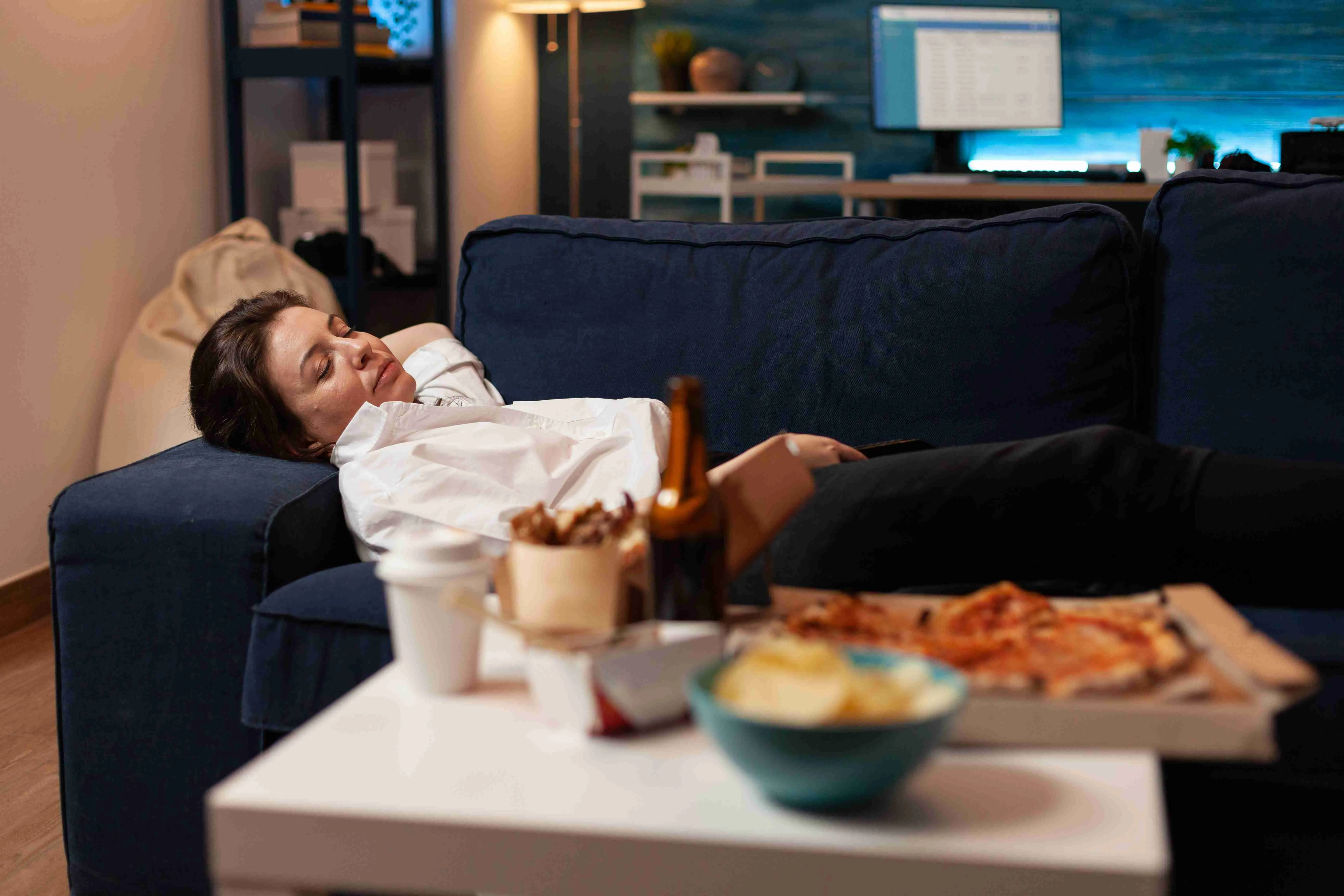 Tired woman falling asleep couch after large fast food takeaway dinner in front of television