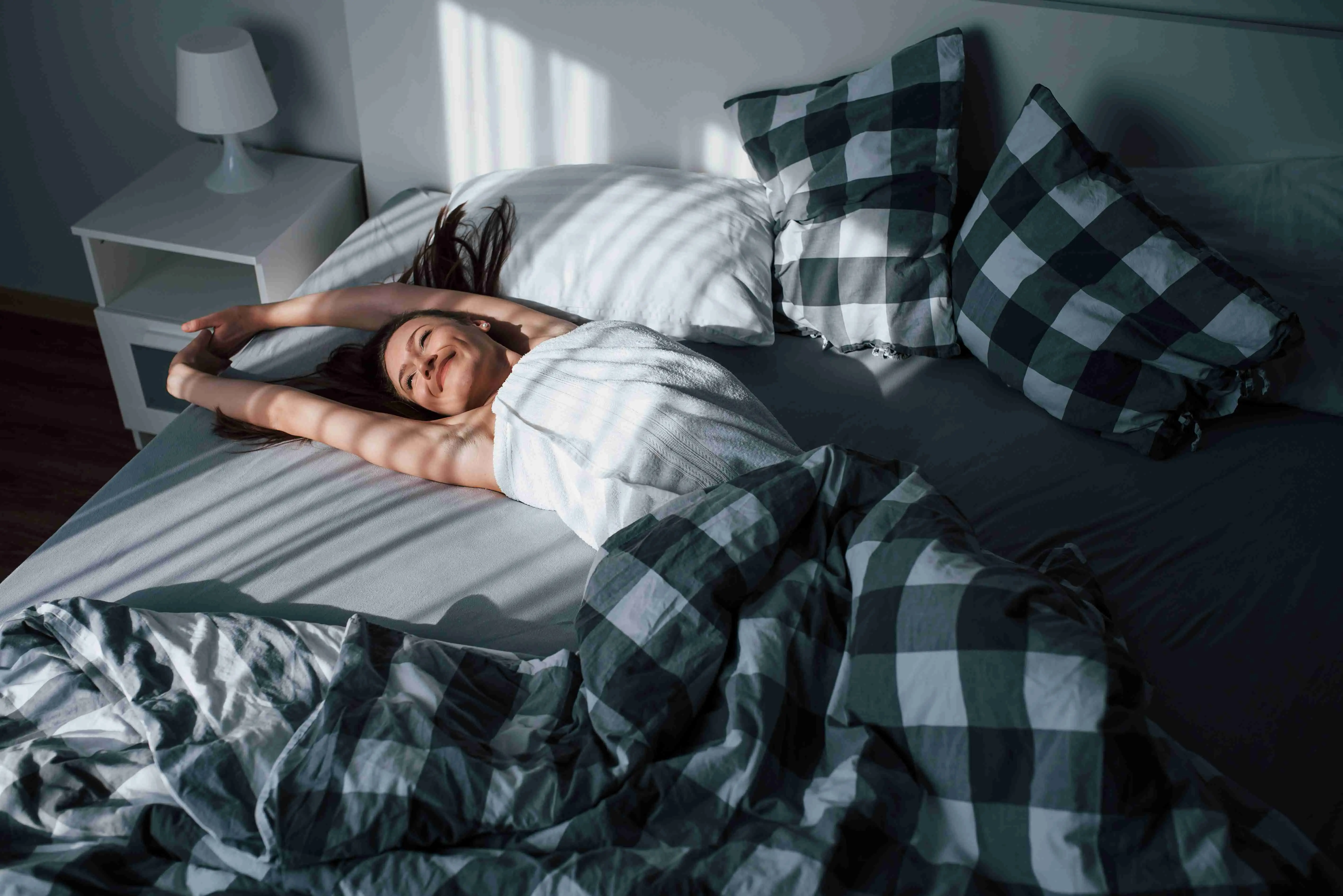 Pretty young woman lying on the bed at morning time in her room.