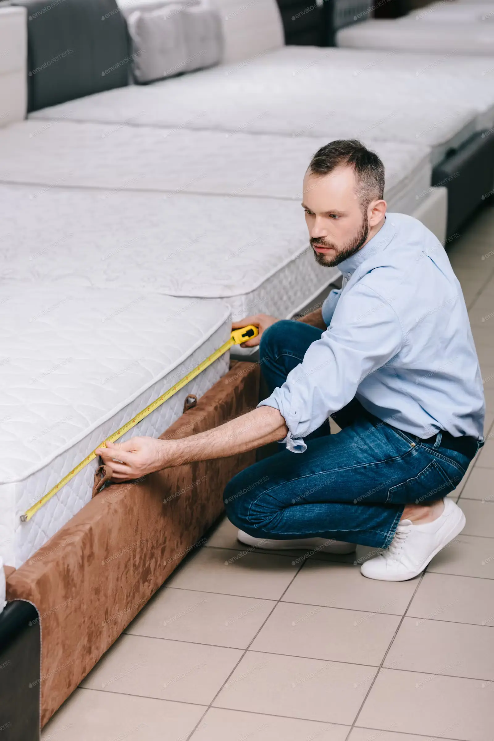 male shopper measuring mattress with measure tape