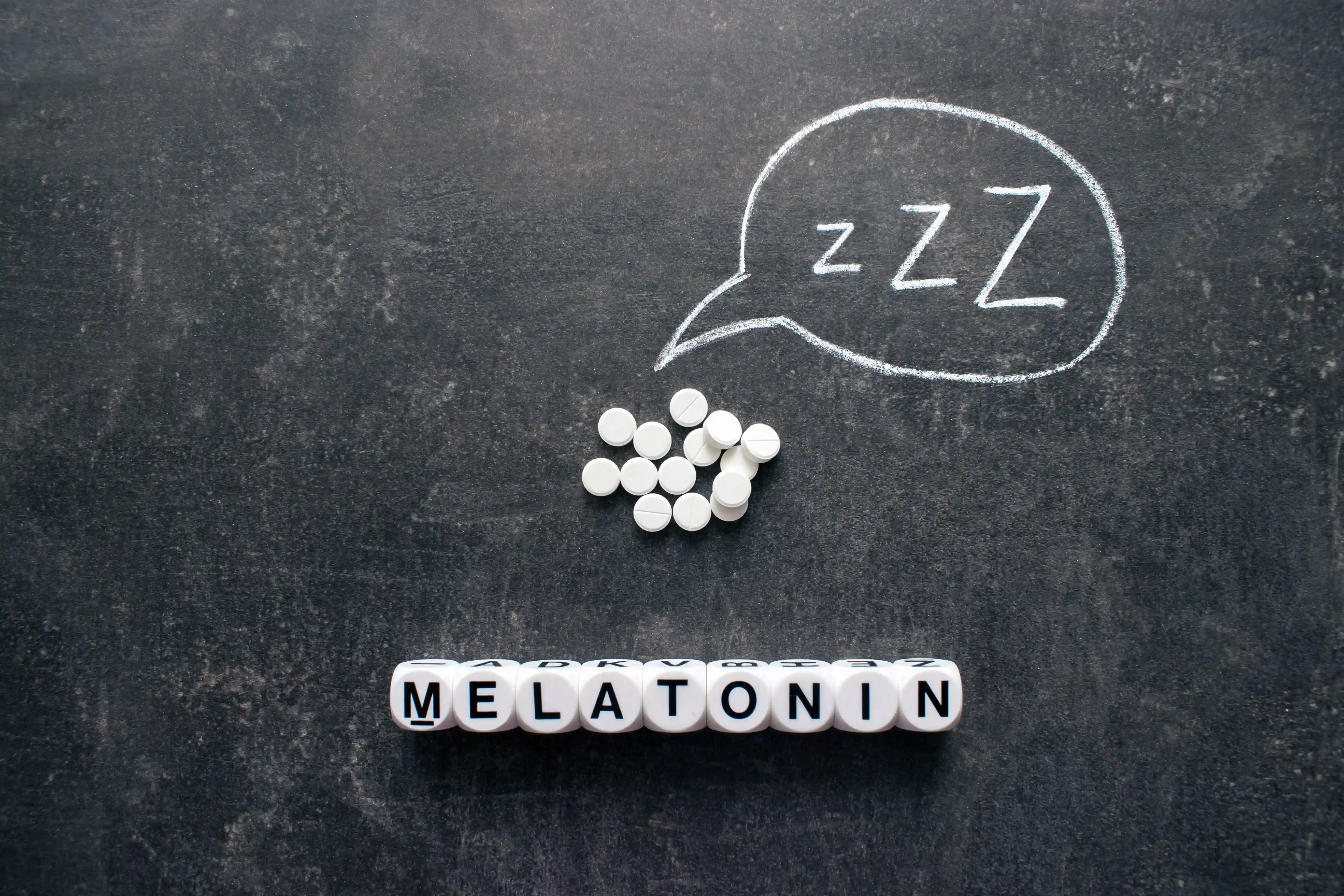 Melatonin tablets beside a glass of water at night