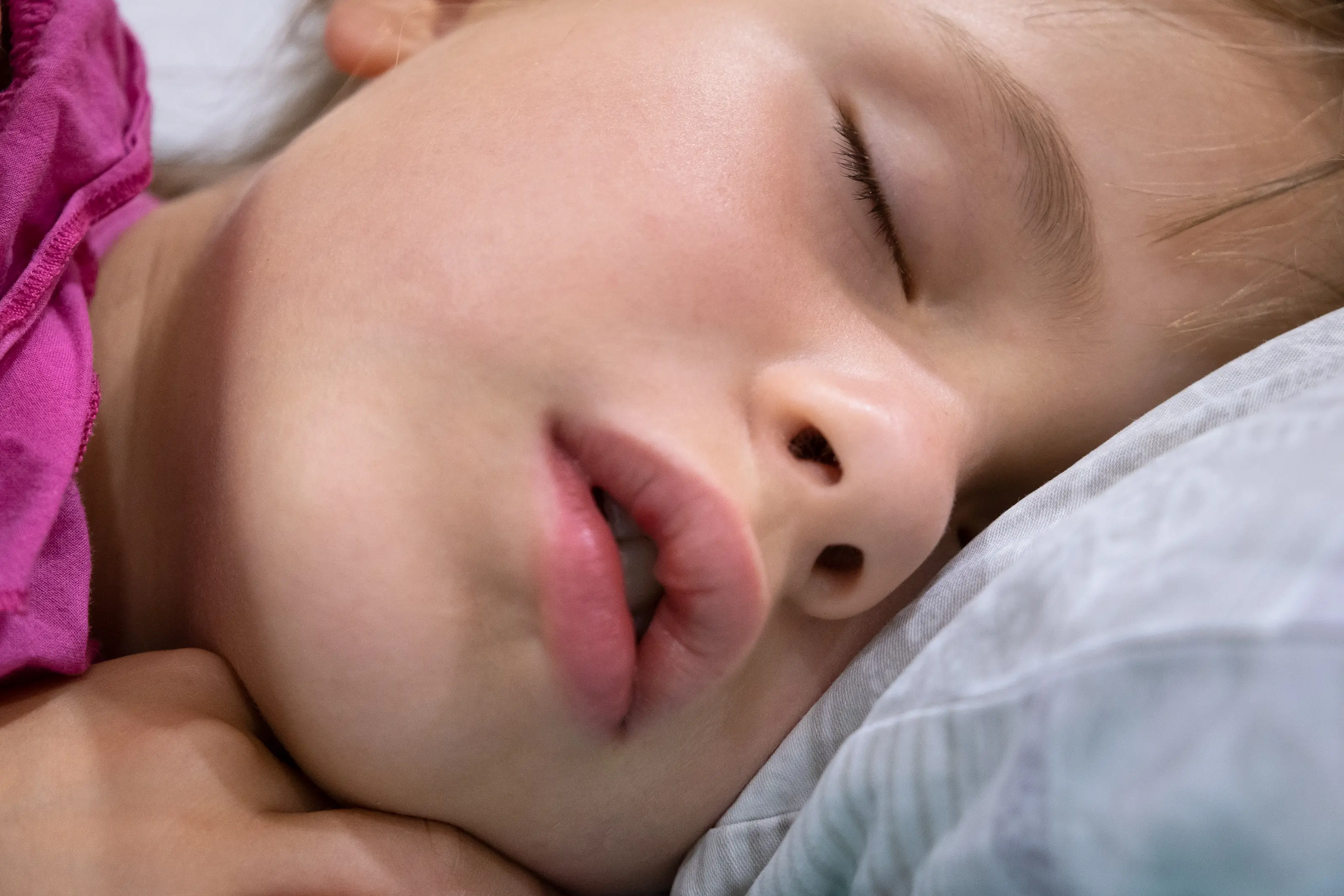 Close up of a face of pretty little child girl with slightly open mouth and scattered around hair