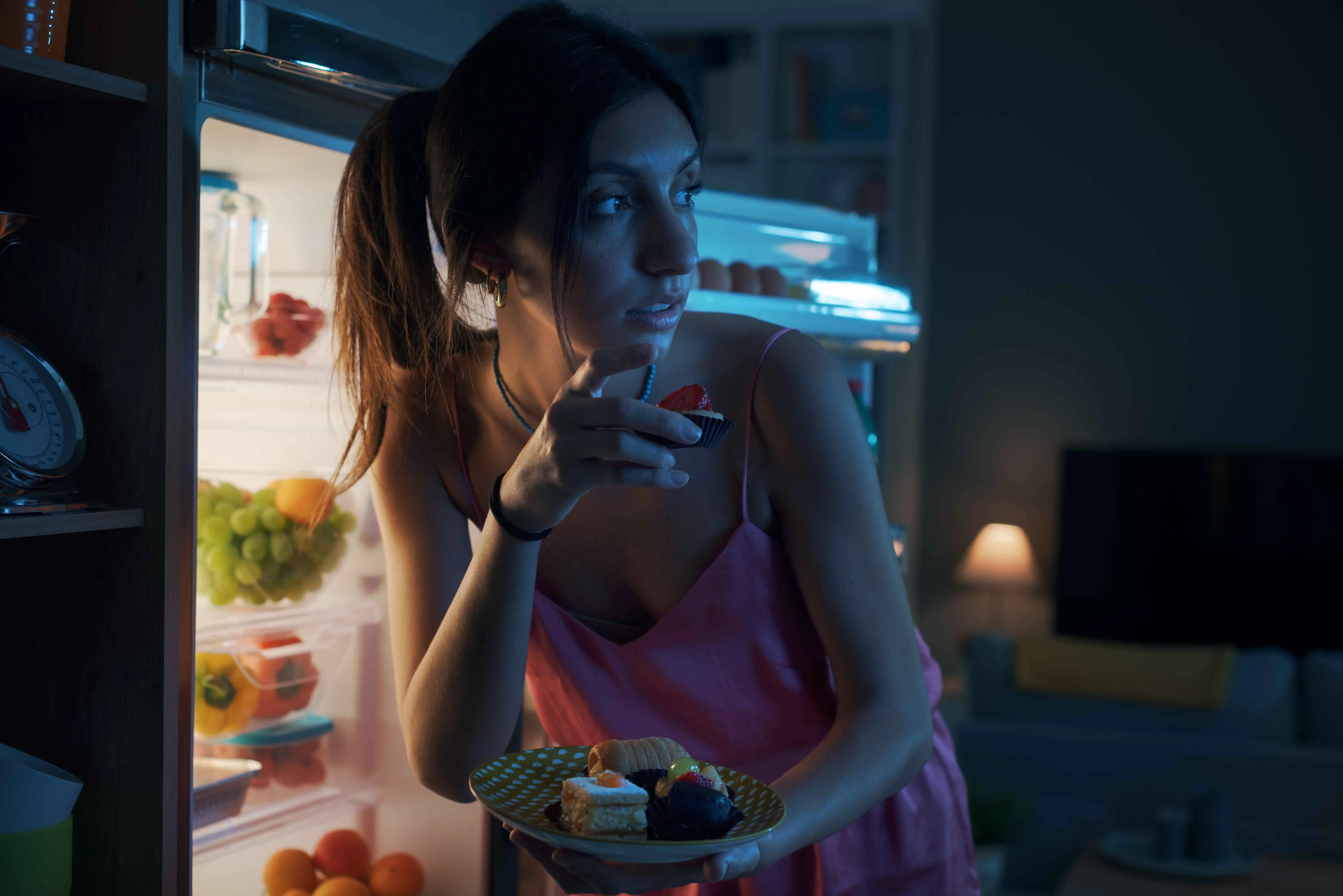 Hungry woman eating sweets at night